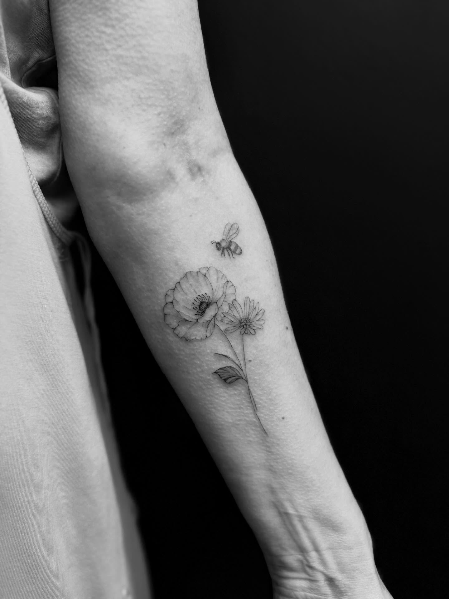 Poppy and bee black and grey tattoo on the forearm by Reverie Studio