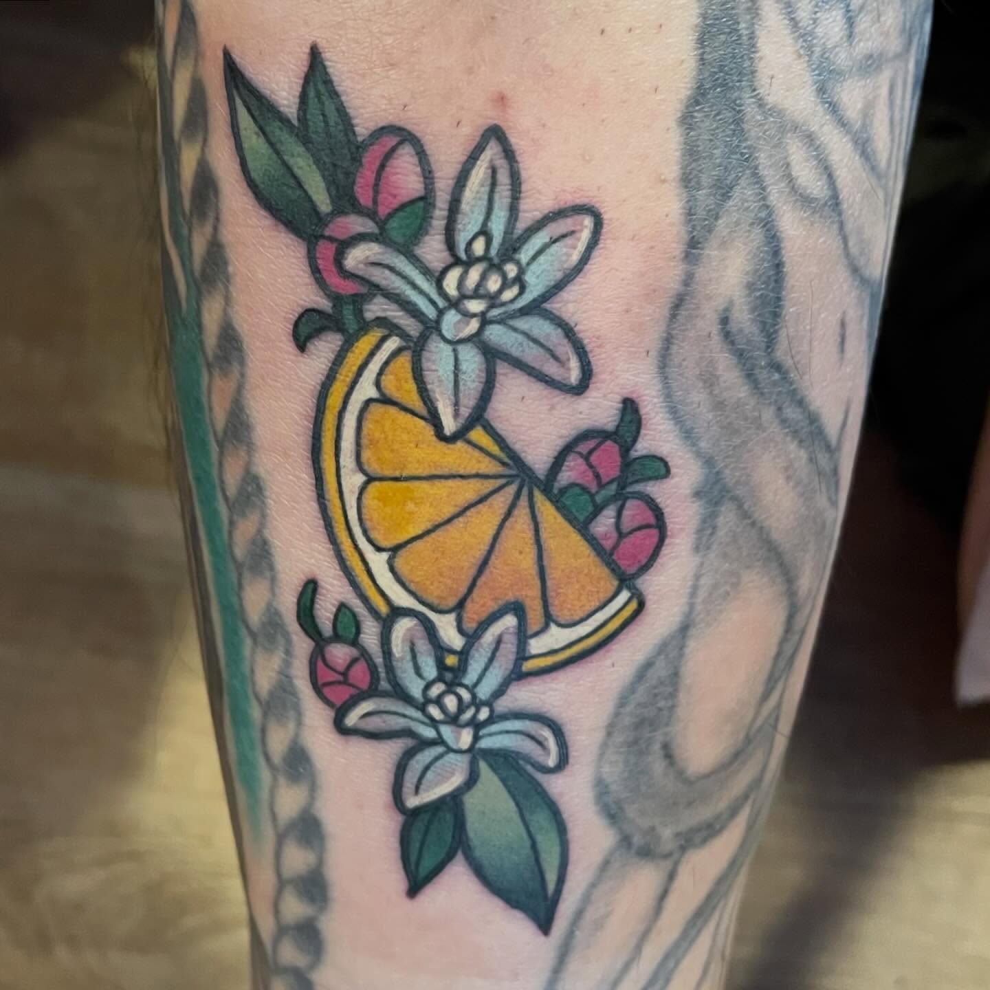 Orange slice and flowers American traditional tattoo on the forearm by Katie Beth