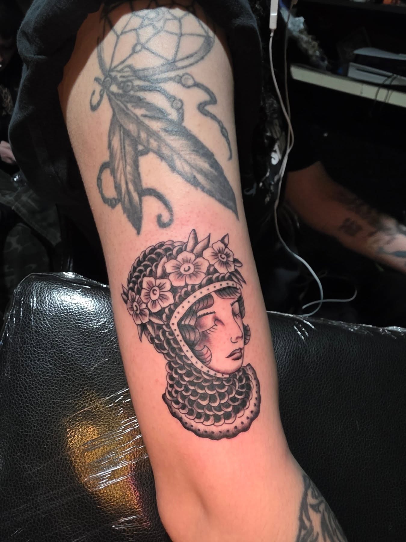 Woman with floral crown black and grey tattoo on the forearm by komik tattoos