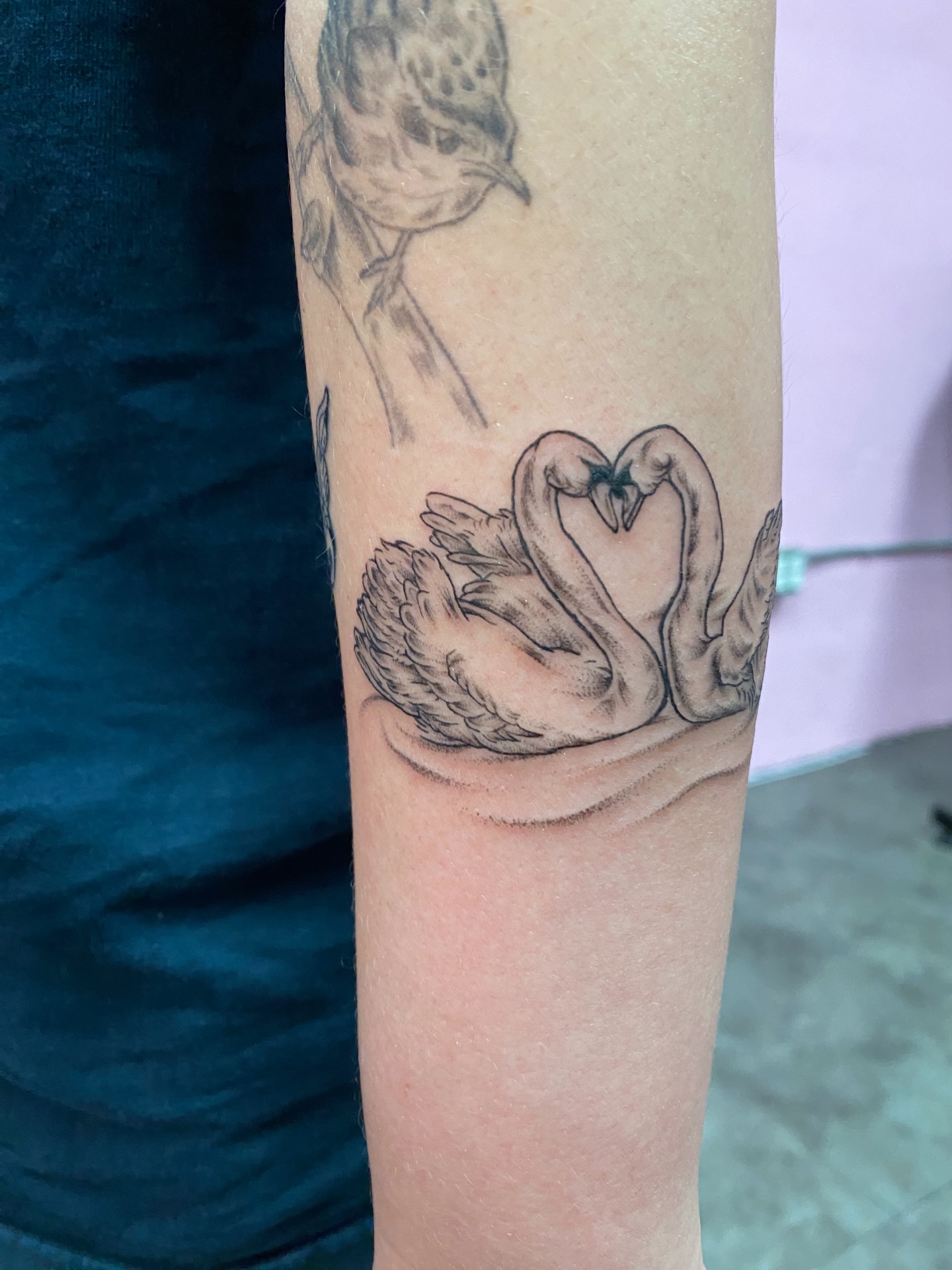 Swans forming heart realism tattoo on the forearm by Mack ๐ Utah Tattoos