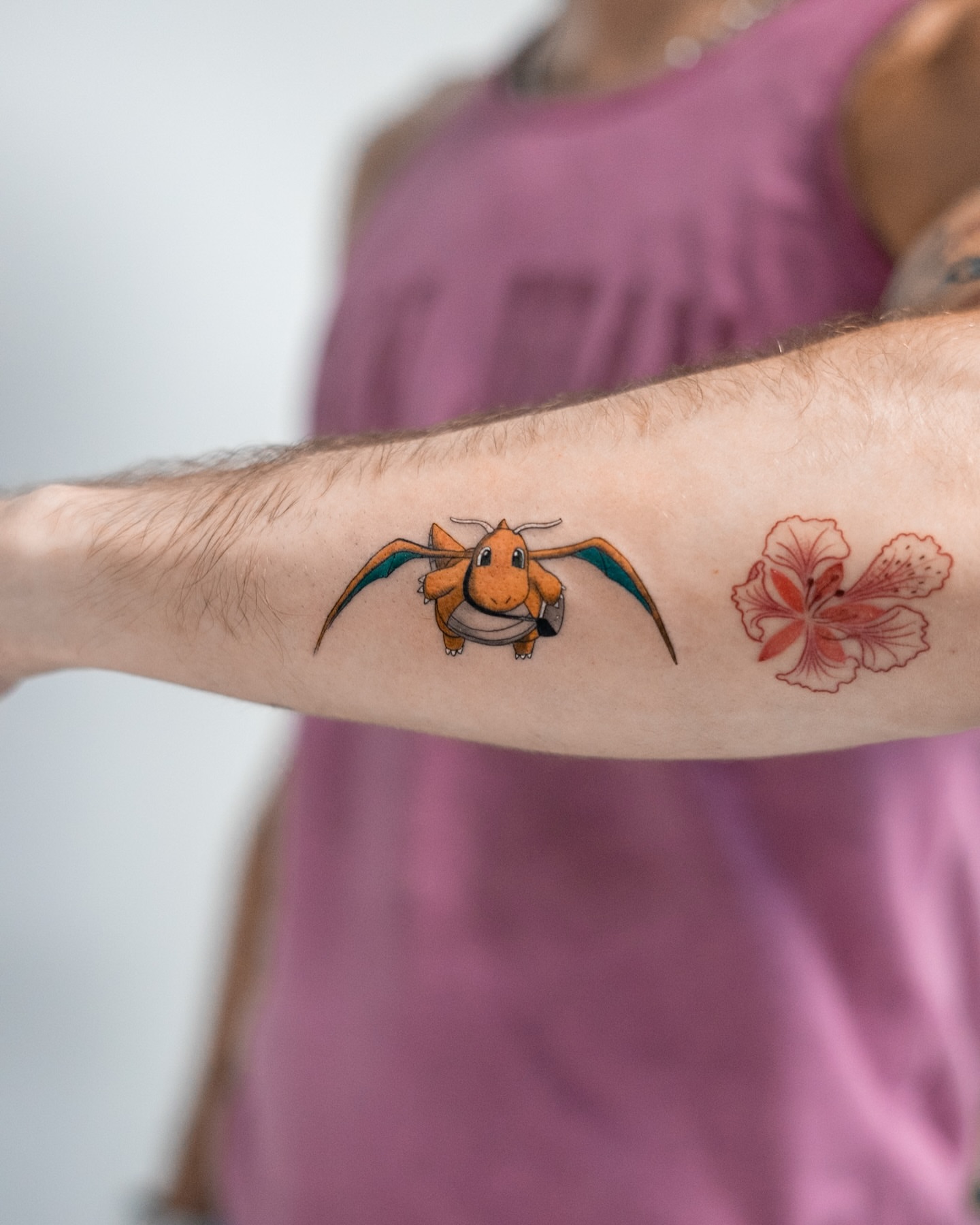 Charizard and flower realism tattoo on the forearm by The Tattoo Plug