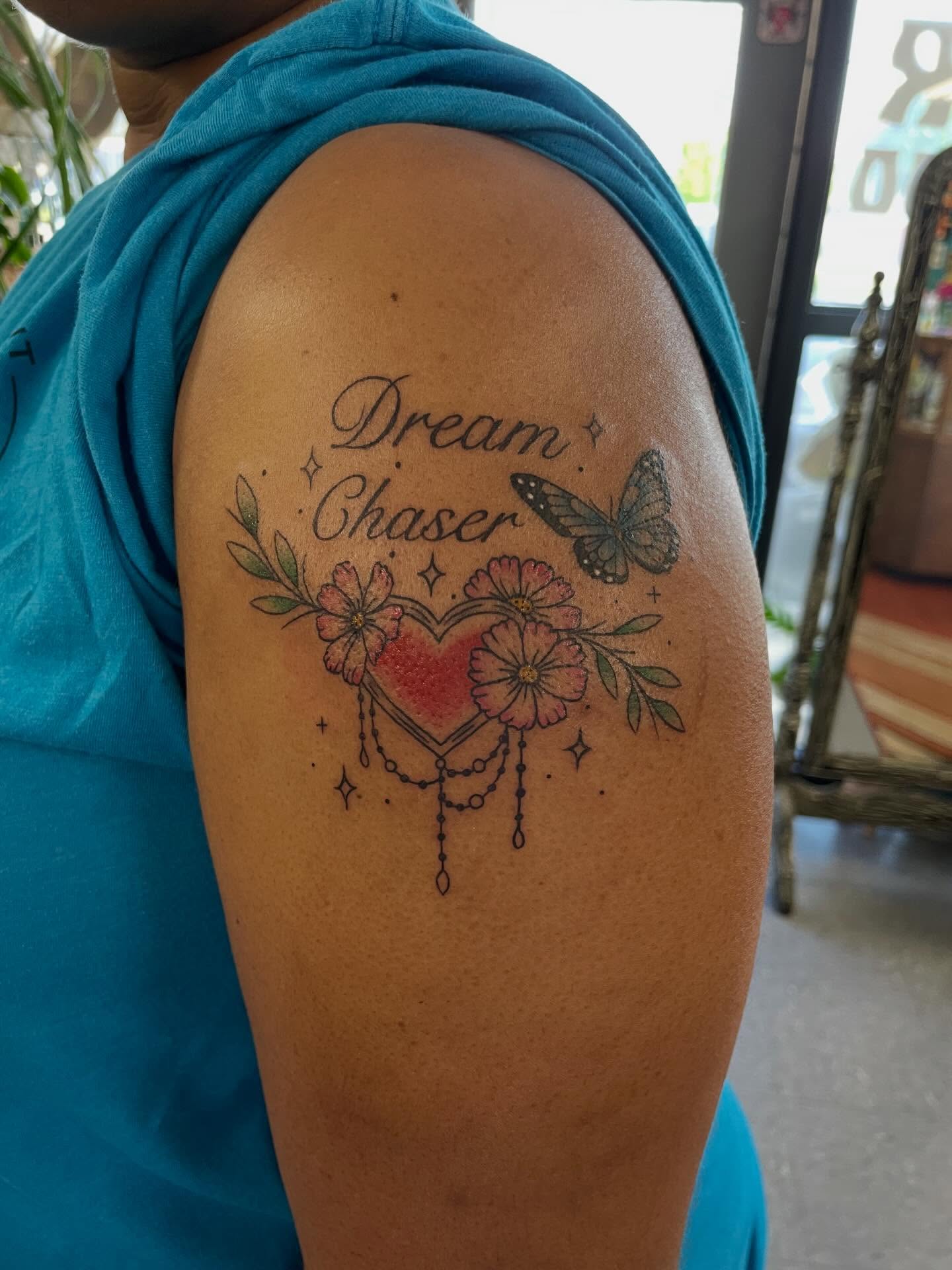 Heart with flowers and butterfly dotwork tattoo on the shoulder by Mallory Moore
