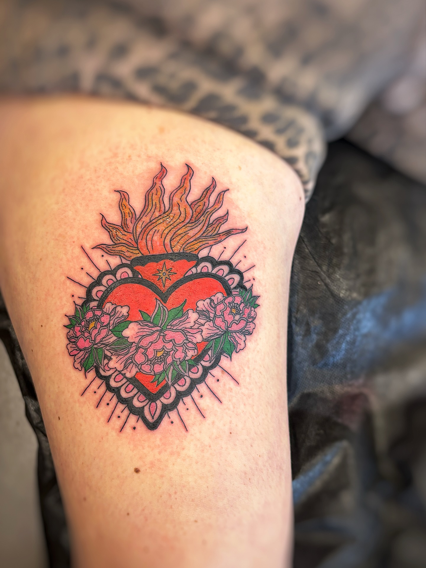 Heart with flowers American traditional tattoo on the thigh by Holly
