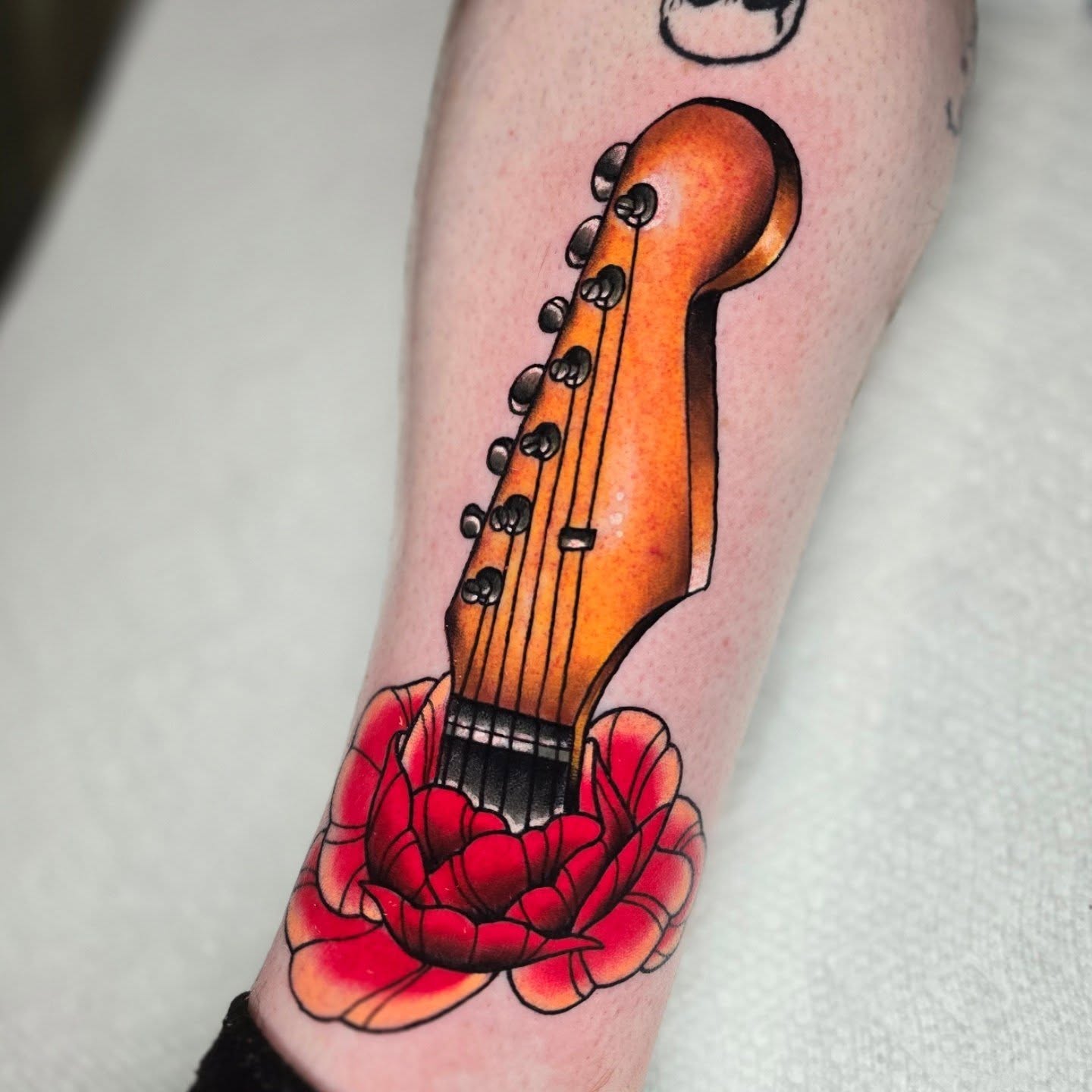 Guitar and flower American traditional tattoo on the forearm by Adison Essig