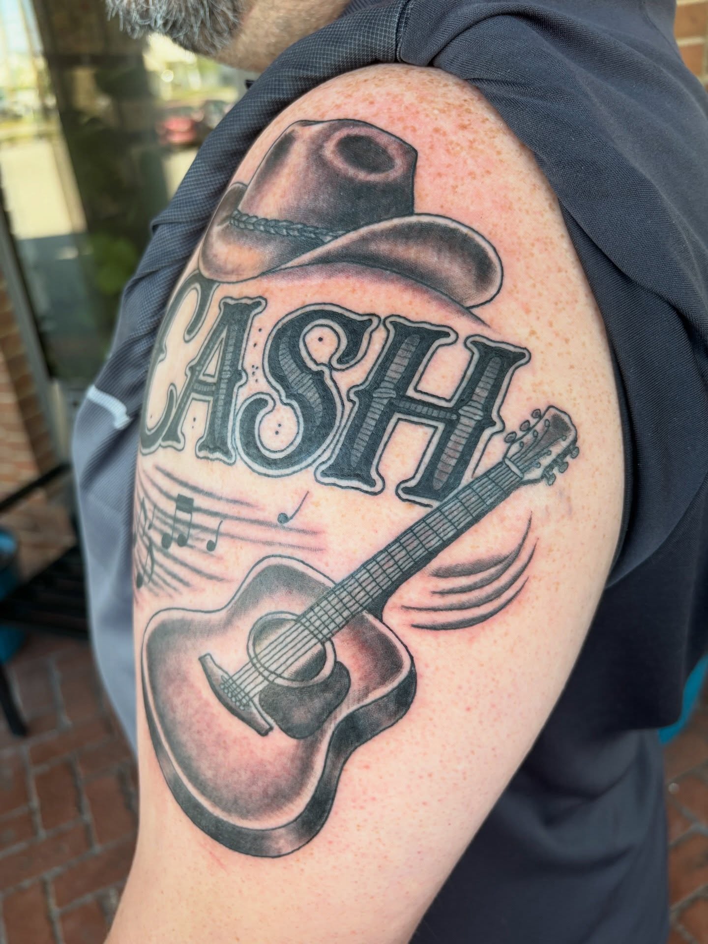 Cash and guitar black and grey tattoo on the shoulder by AARON MASTERS - Tattoo Artist