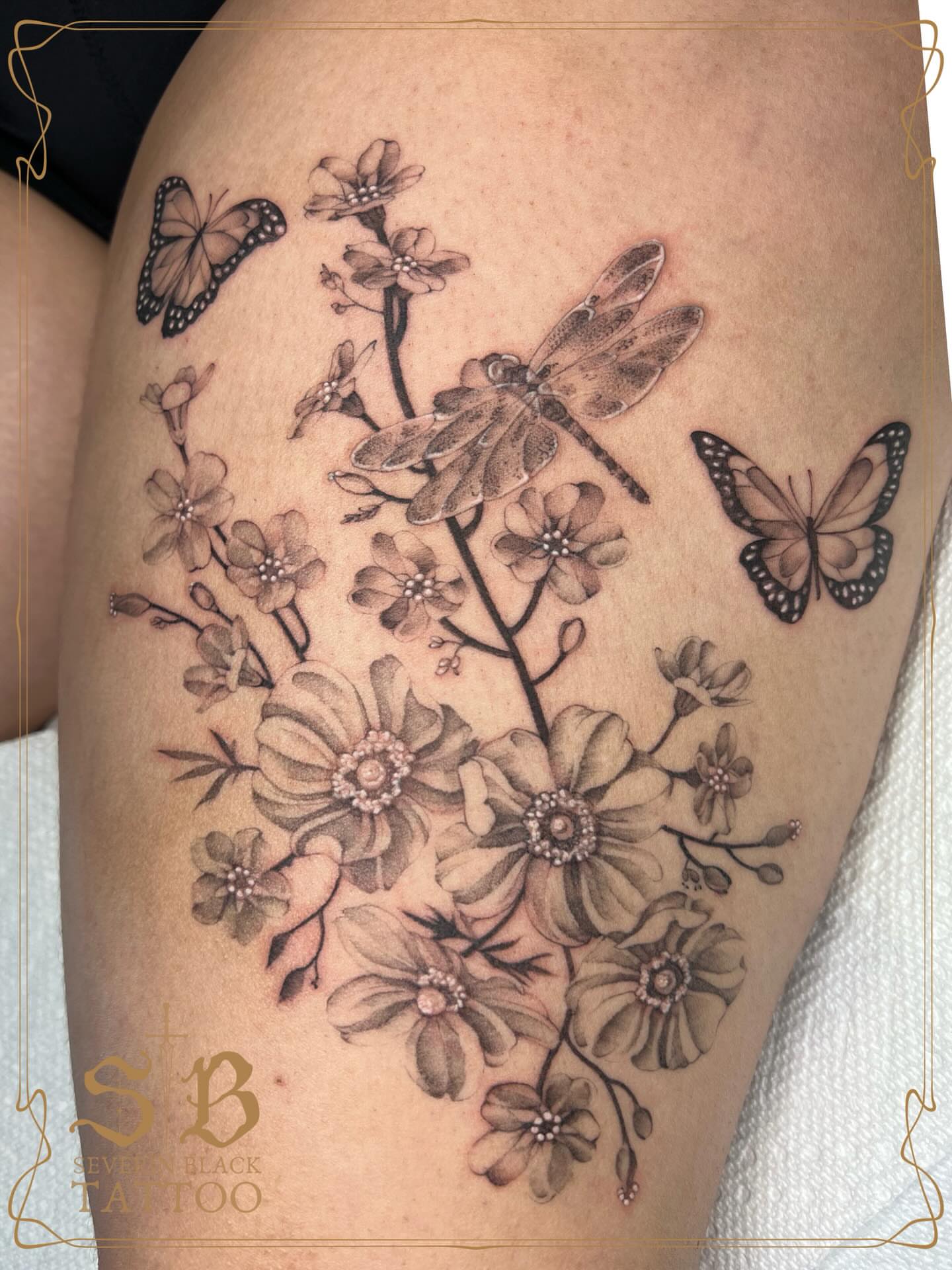 Flowers and butterflies realism tattoo on the thigh by Severin Black