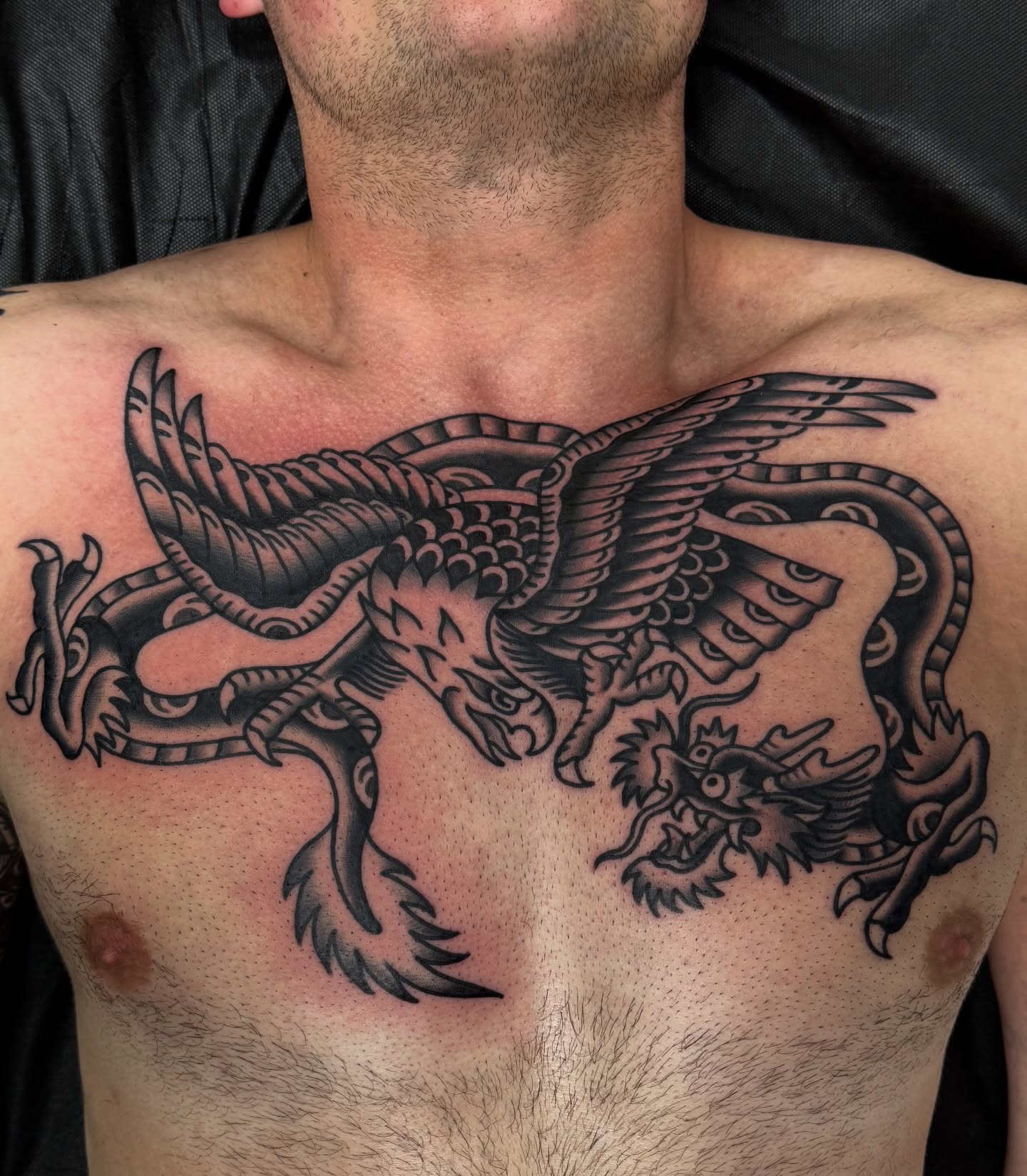 Dragon and phoenix black and grey tattoo on the chest by Joey Burdette Tattoos