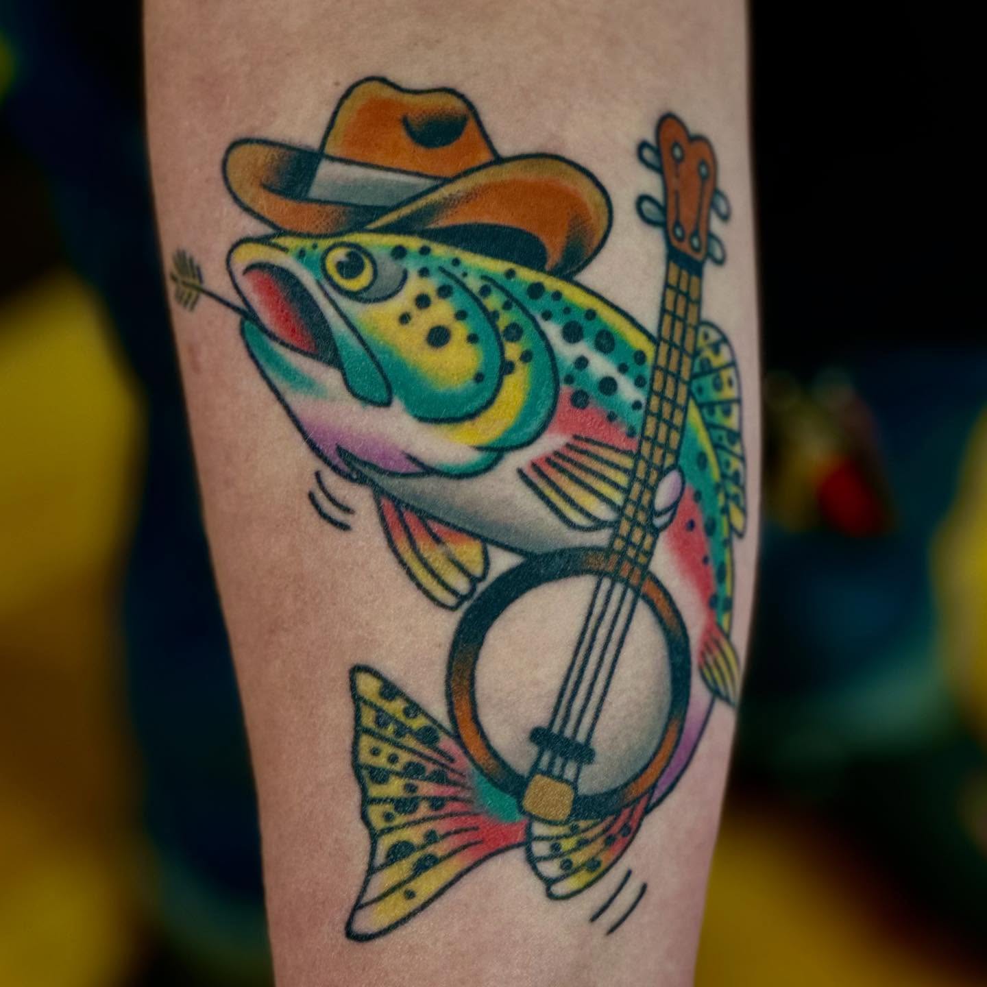 Rainbow trout playing banjo American traditional tattoo on the forearm by Dylan Curry