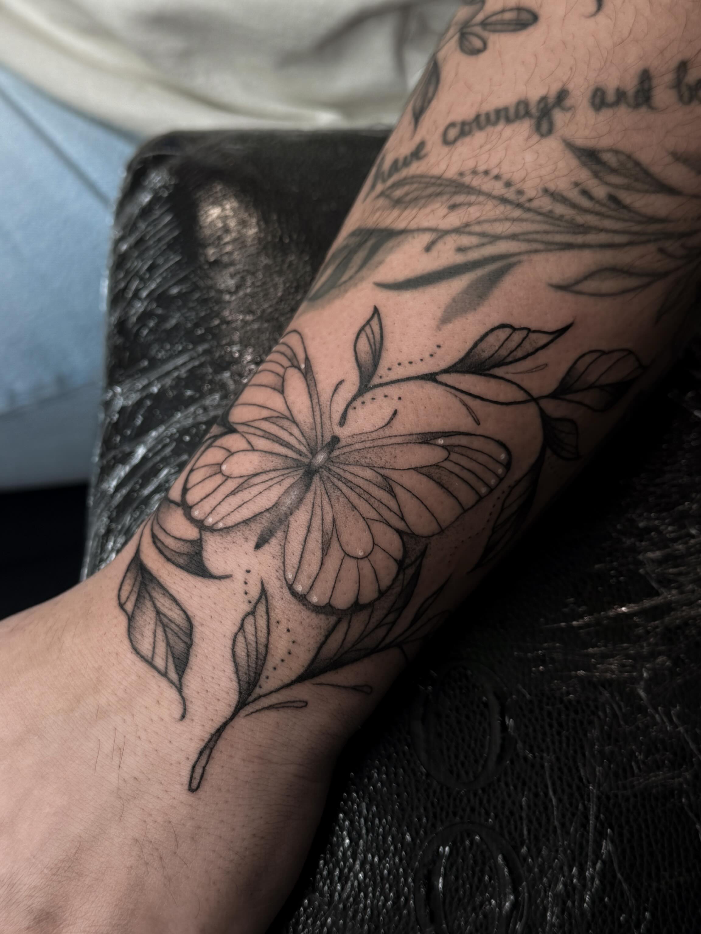 Butterfly and flower black and grey tattoo on the forearm by Susie Maj