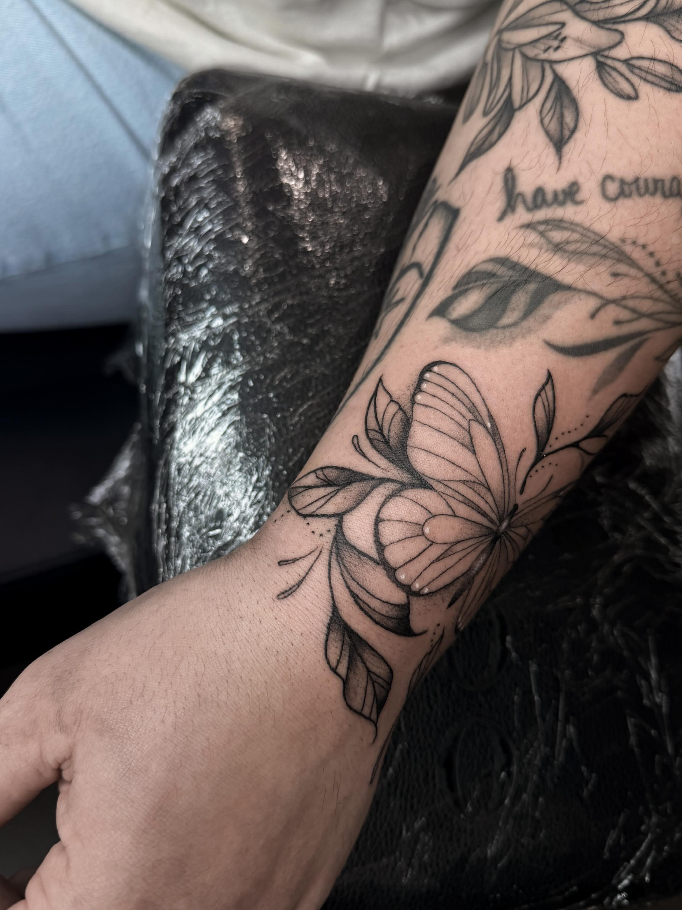 Butterfly and flower black and grey tattoo on the forearm by Susie Maj