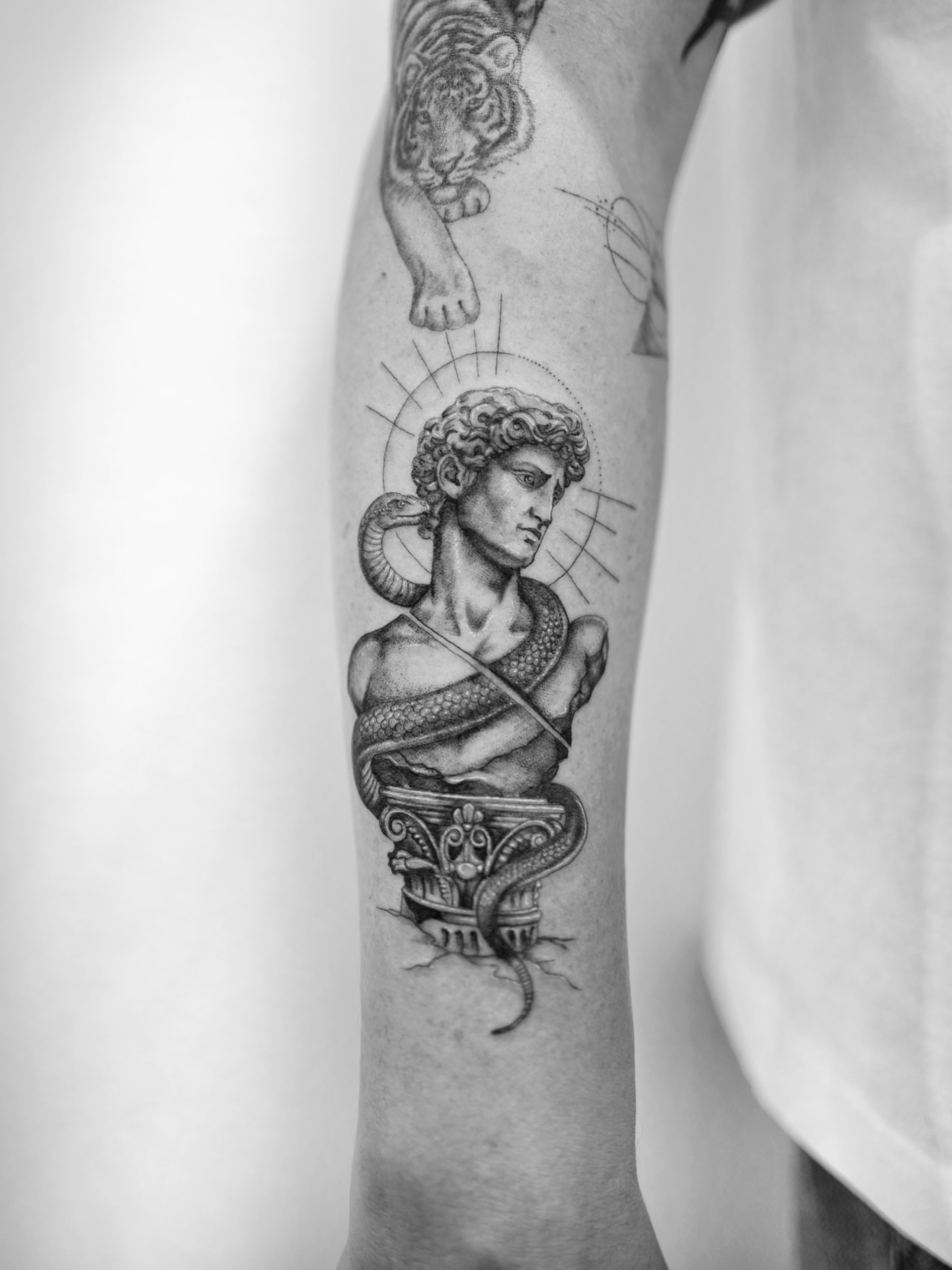 Statue bust with snake realism tattoo on the forearm by Ross Clark Tattoos