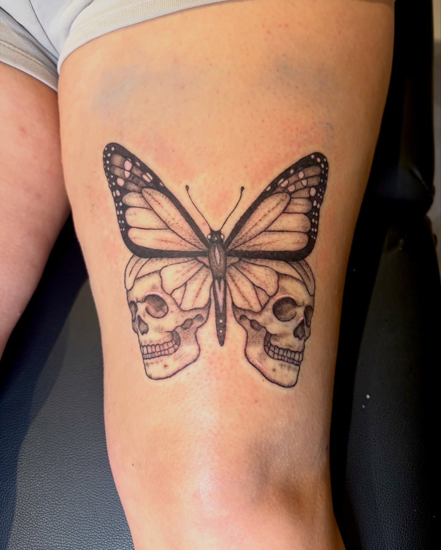 Butterfly and skulls realism tattoo on the thigh by Emily, Monticello, Iowa