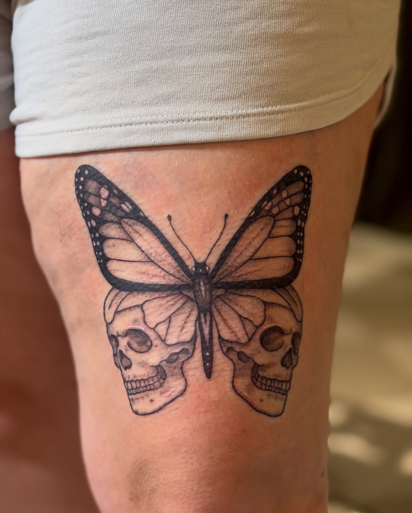 Butterfly and skulls realism tattoo on the thigh by Emily, Monticello, Iowa