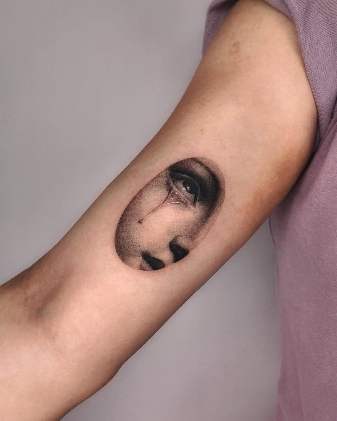 Crying face surrealism tattoo on the forearm by Gabriel