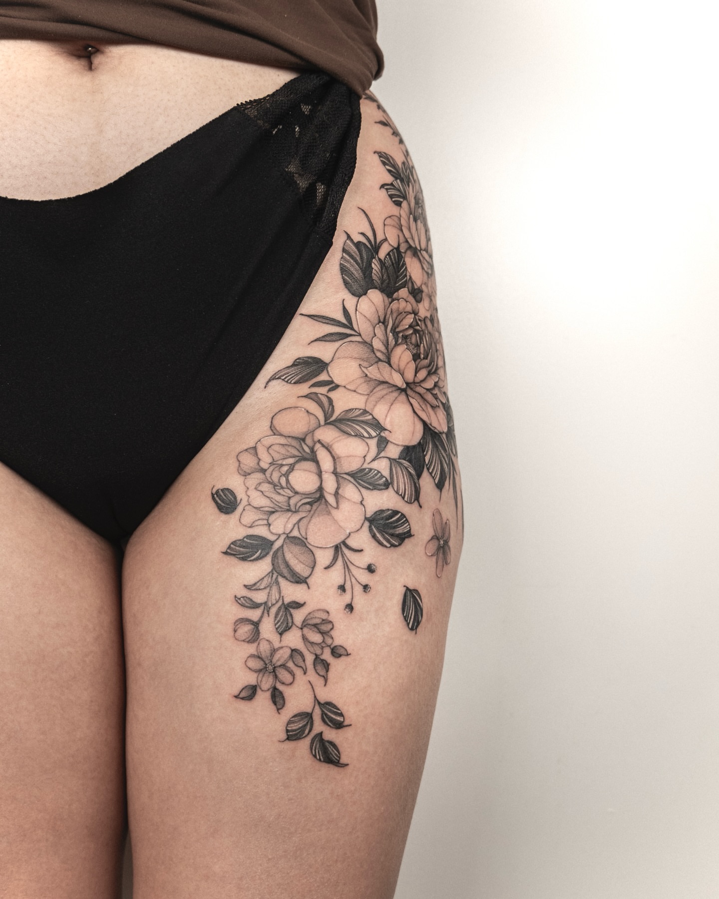 Floral bouquet black and grey tattoo on the thigh by Wong Lee