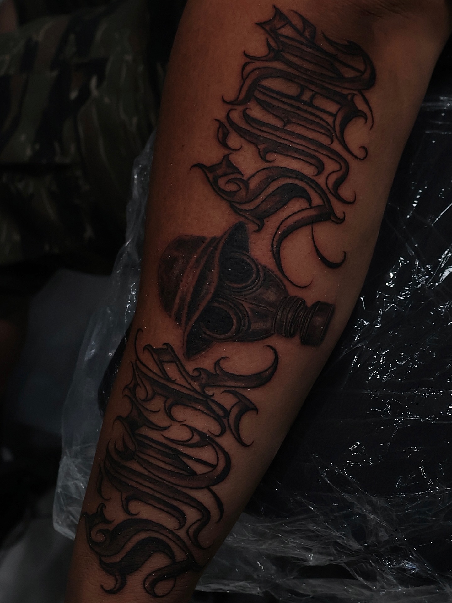 Lamp and ornamental script realism tattoo on the forearm by Joey Moreno