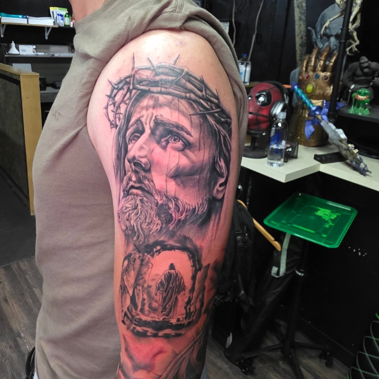 Religious figure realism tattoo on the upper arm by komik tattoos