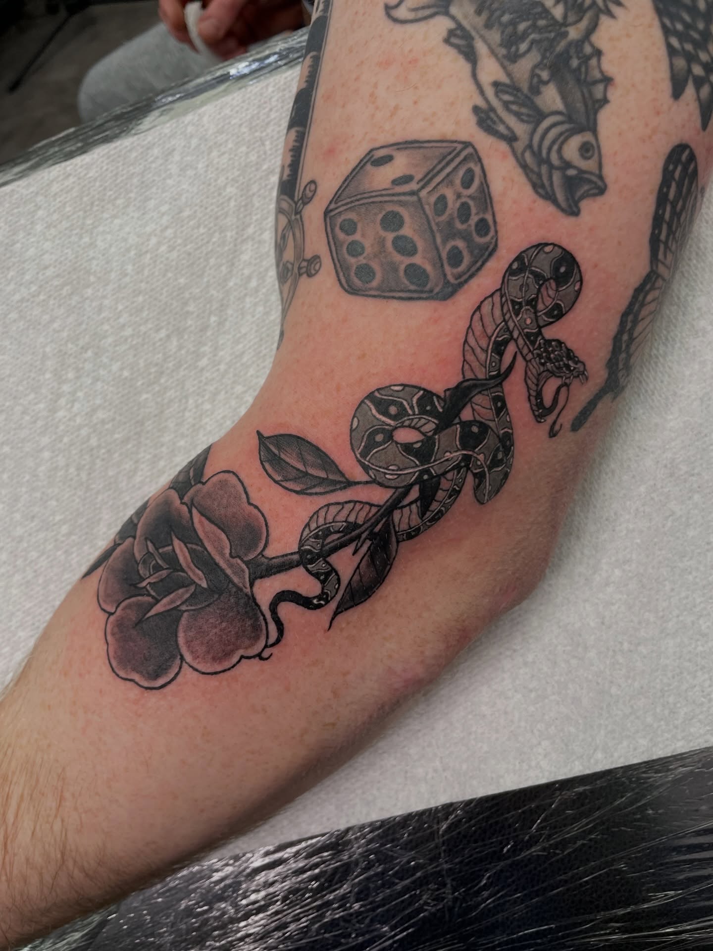 Snake and peony black and grey tattoo on the forearm by Joey Taylor