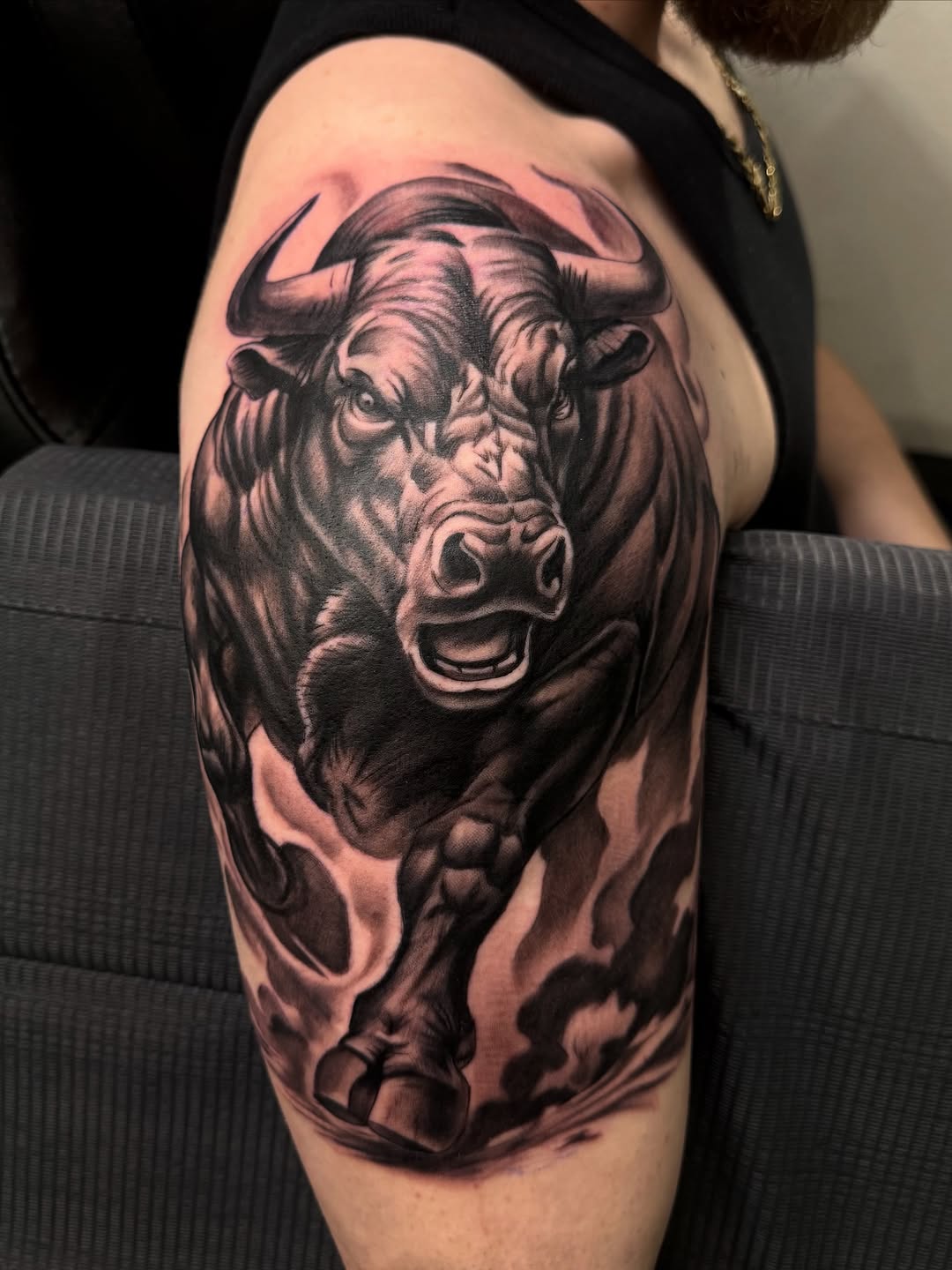 Charging bull realism tattoo on the upper arm by Eduardo Chaparro