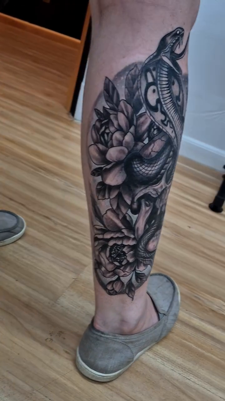 Snake and skull with flowers realism tattoo by Chris TL Jones