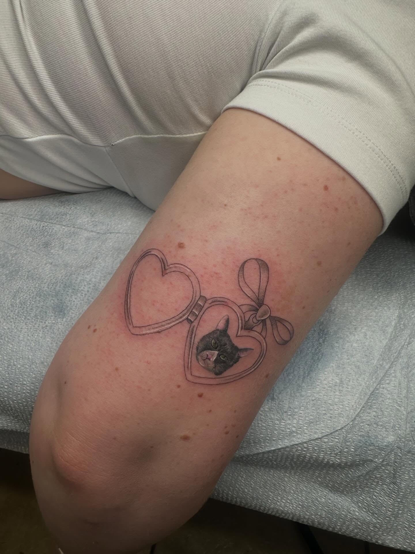 Heart locket with cat realism tattoo on the forearm by Alex Gunshefski
