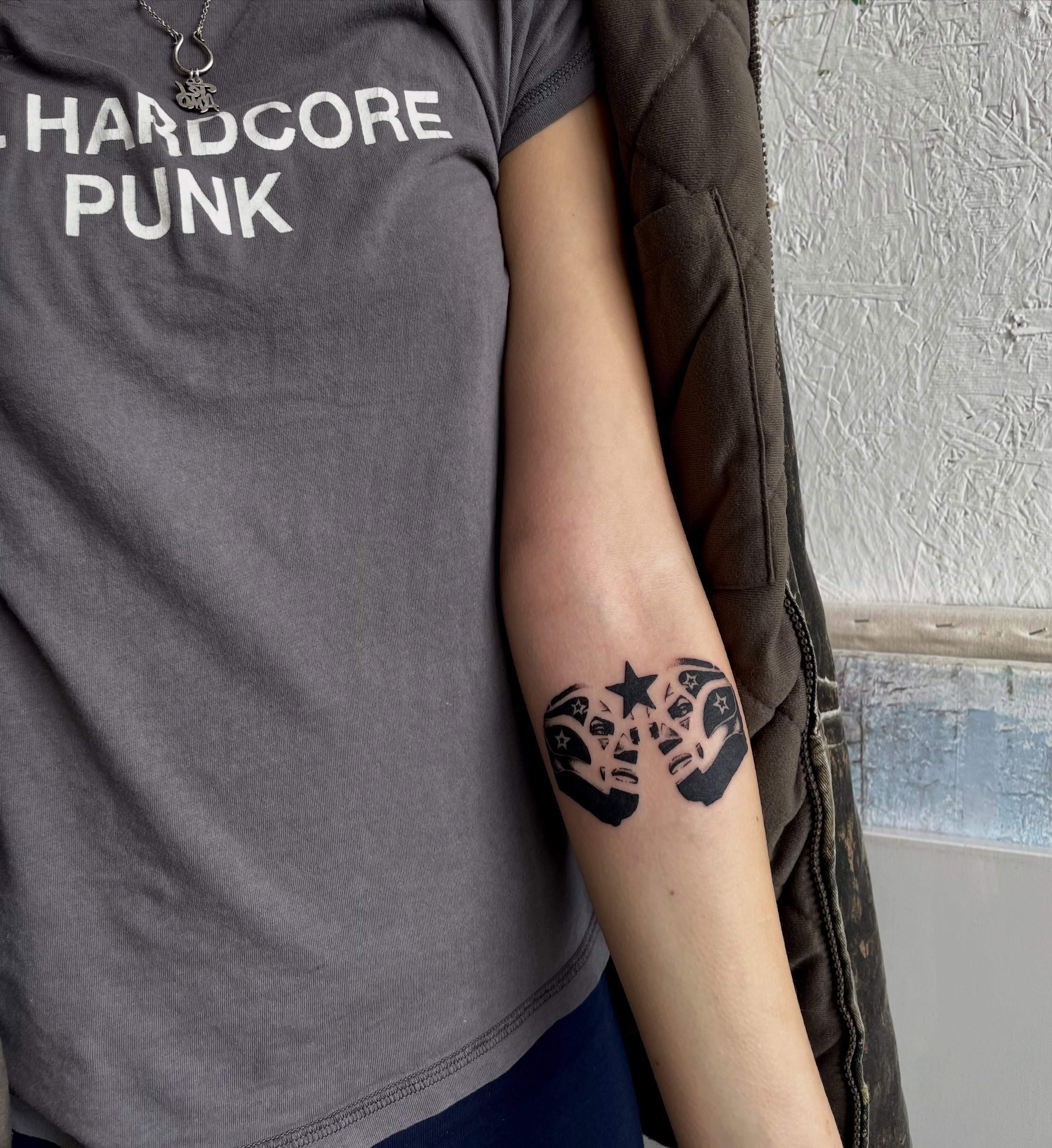 Mask with stars black and grey tattoo on the forearm by bisabuelita
