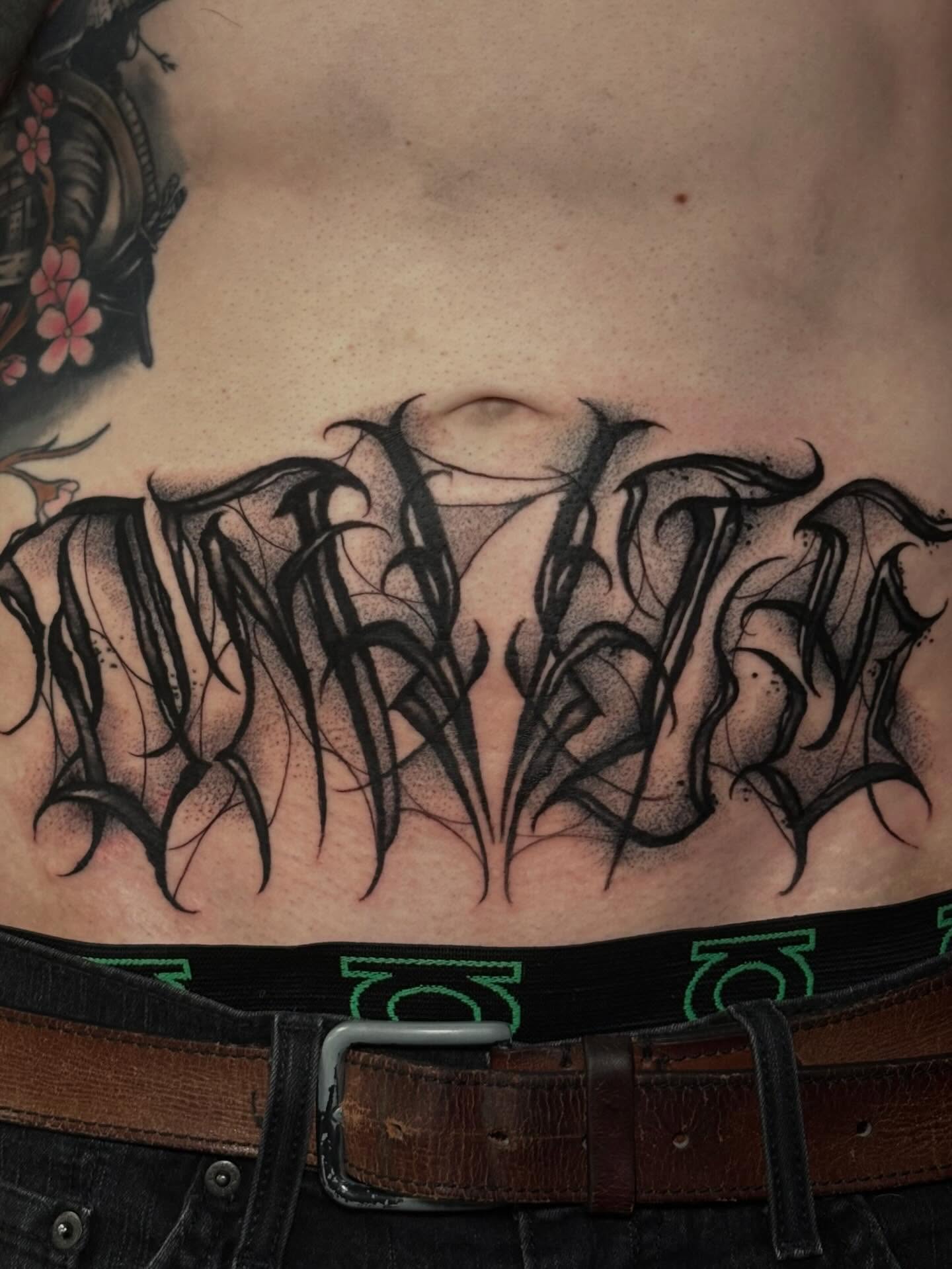 Gothic script black and grey tattoo on the torso by Trusty Dizon Tattoo Artist