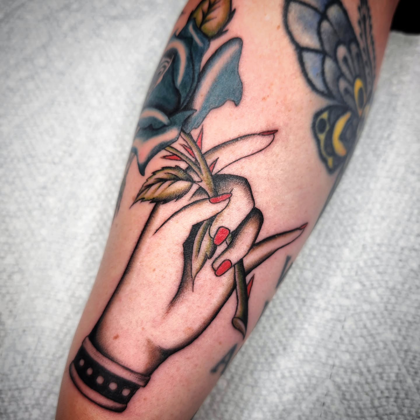 Hands holding plant American traditional tattoo on the forearm by Kelly Zito