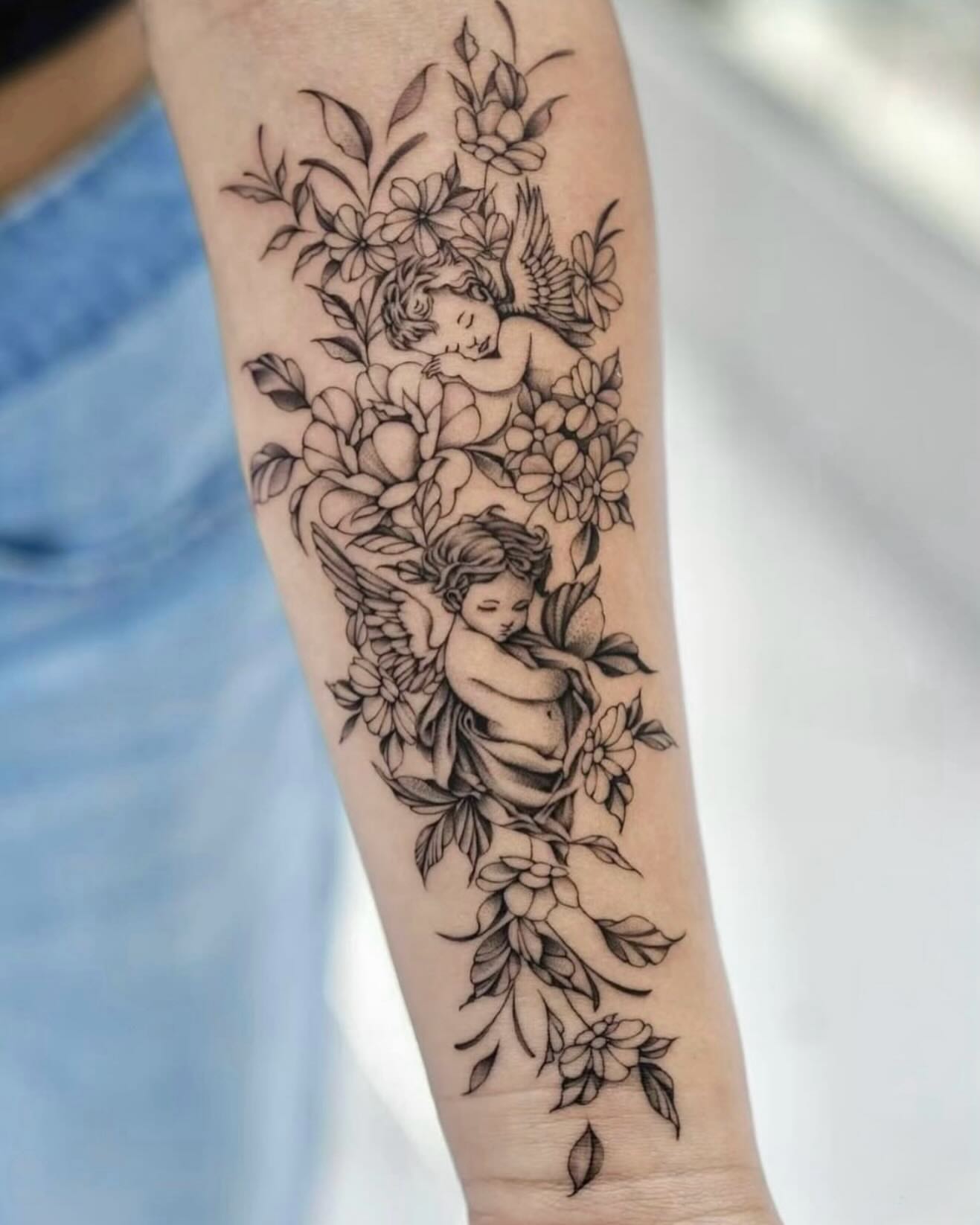 Cherubs and flowers black and grey tattoo on the forearm by Raytattooist
