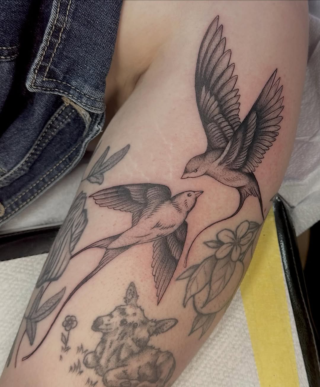 Two swallows and flowers fine line tattoo on the forearm by Lia Massari