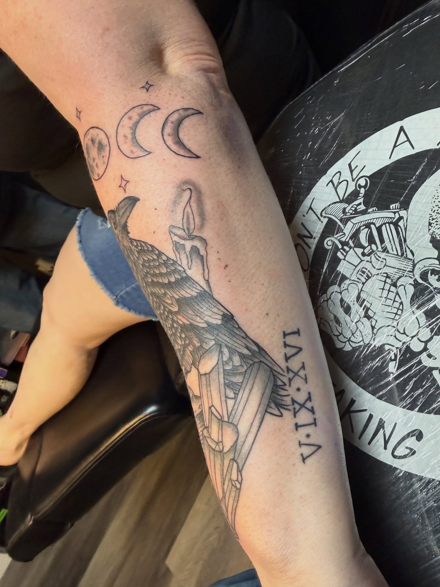 Bird holding candle black and grey tattoo on the forearm by Justin George