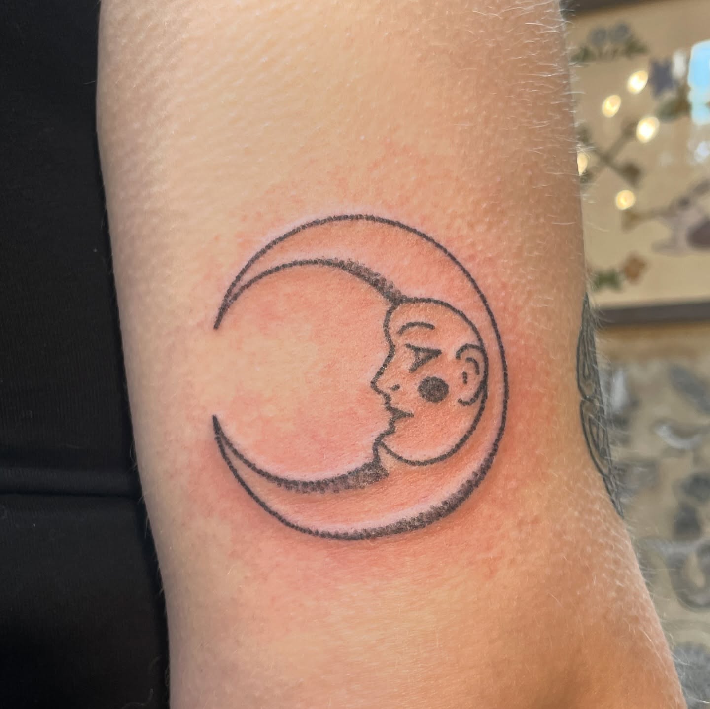 Moon and face minimalist tattoo on the forearm by Roe
