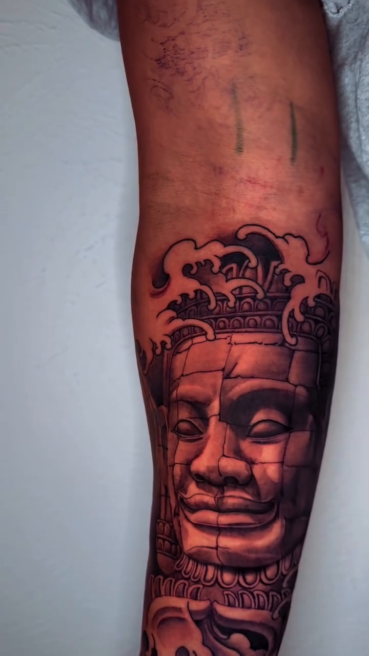 Angkor Wat face tattoo with waves realism tattoo on the forearm by Mike Nance