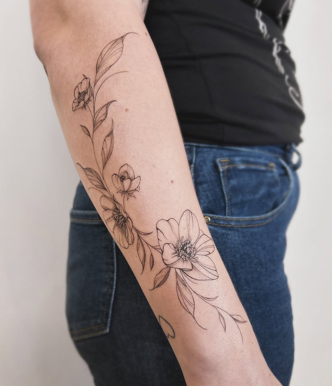 Floral branch fine line tattoo on the forearm by Helly March
