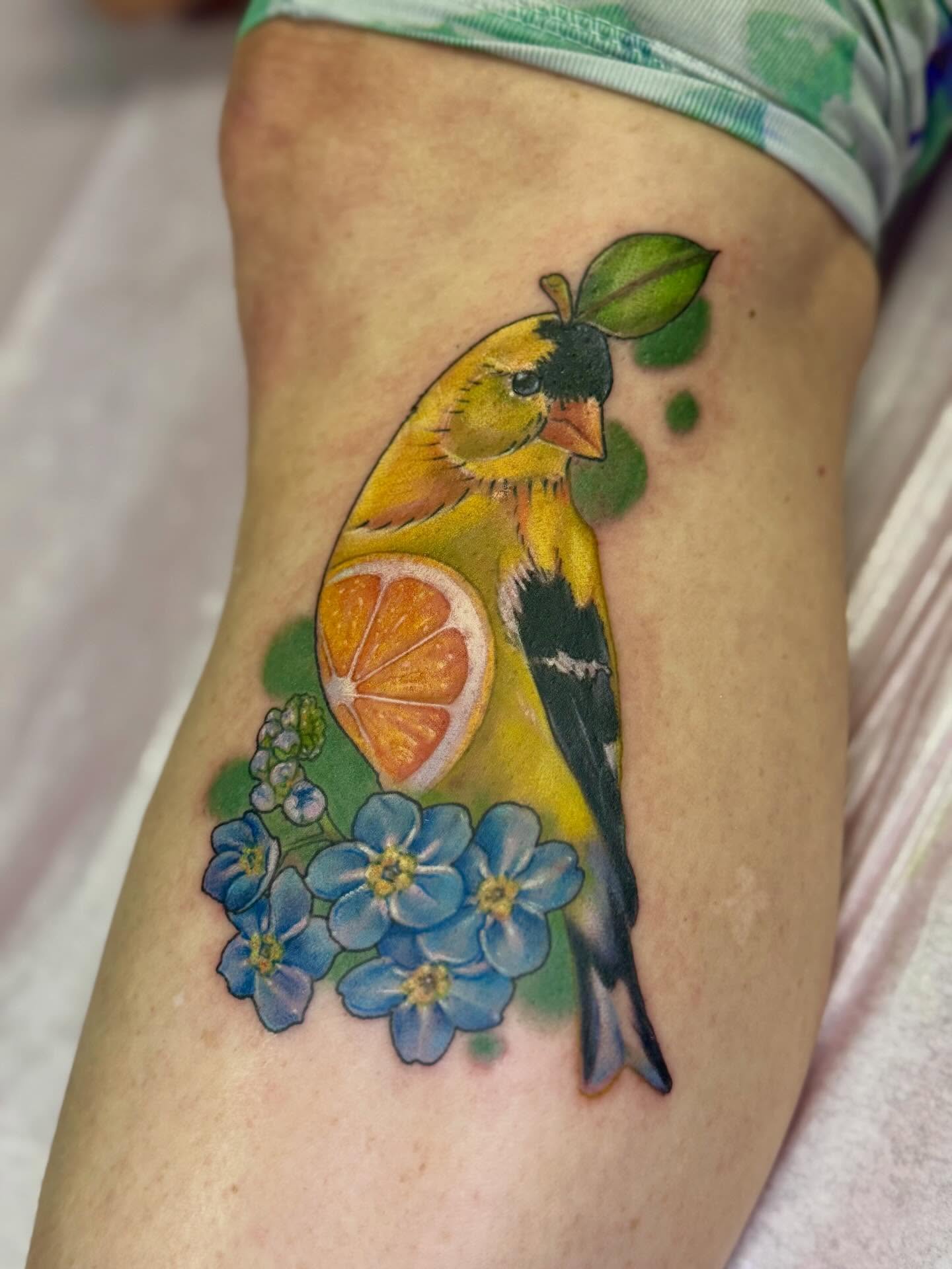 Goldfinch and orange slice realism tattoo on the thigh by Eileen Joyce