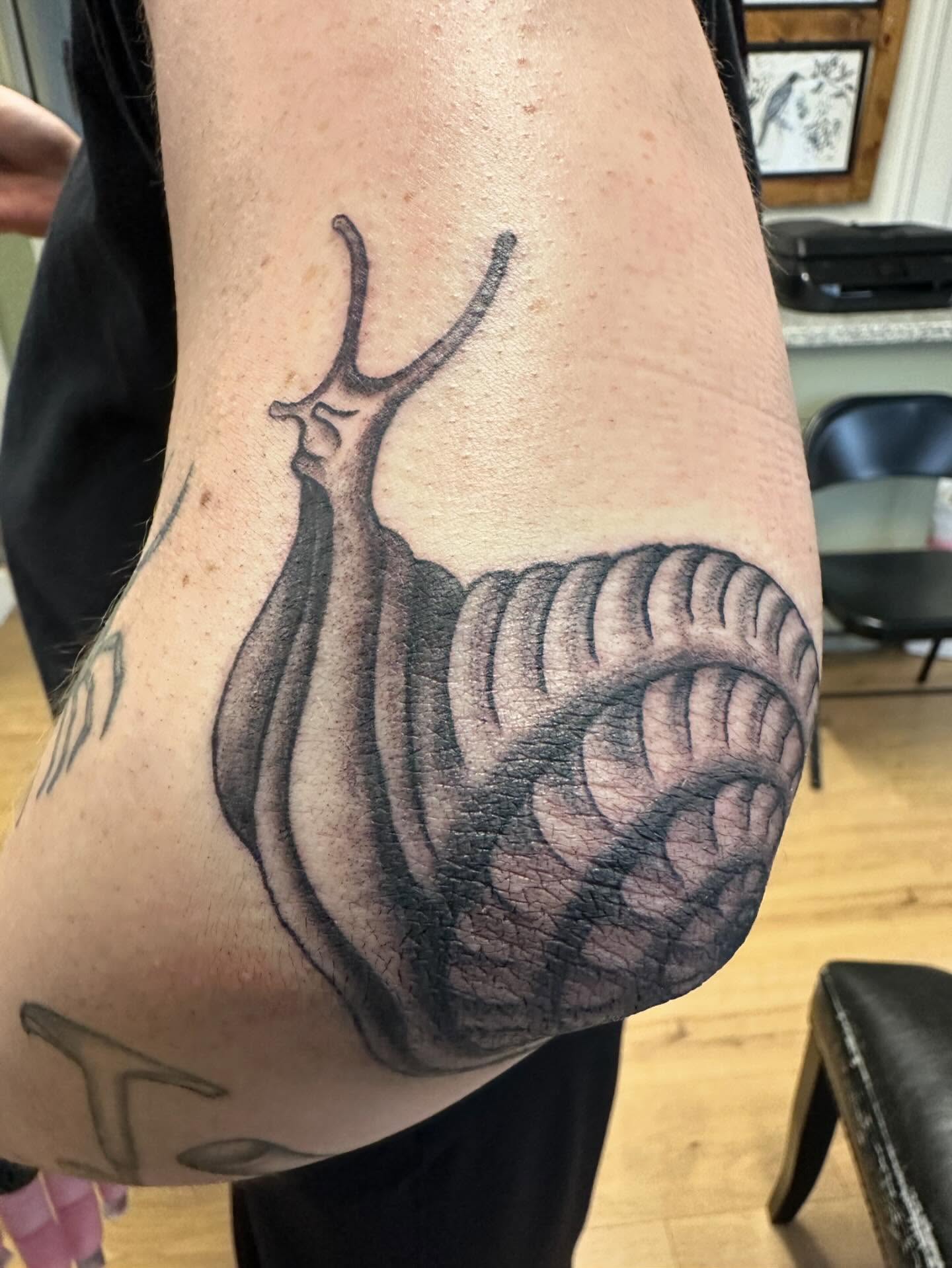 Snail black and grey tattoo on the forearm by Kaylee Woods