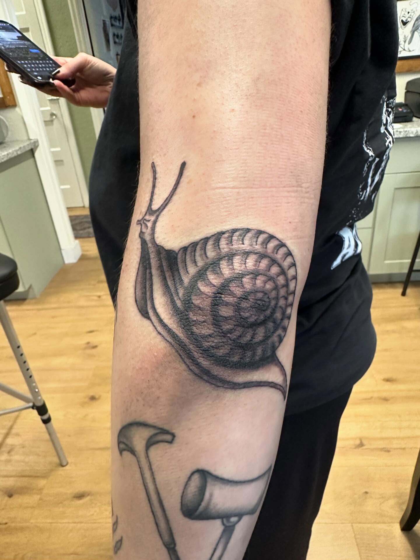 Snail realism tattoo on the forearm by Kaylee Woods