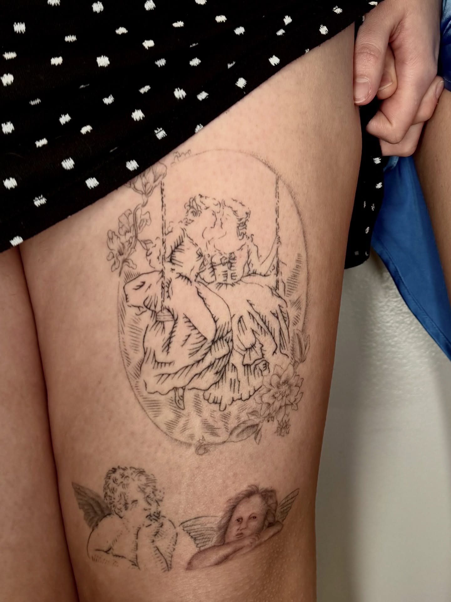 Swinging couple with cherubs realism tattoo on the thigh by Ian Saner