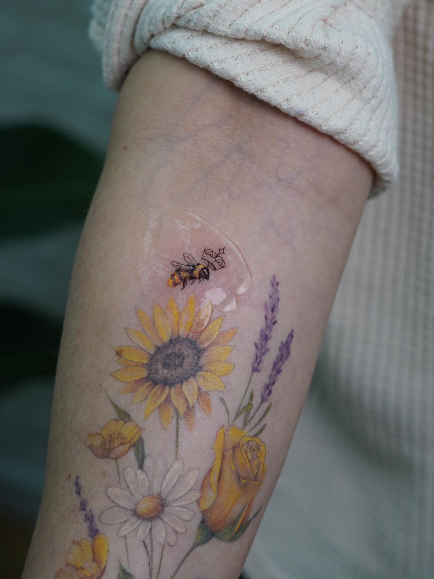 Flowers and bee realism tattoo on the forearm by Danae Andino