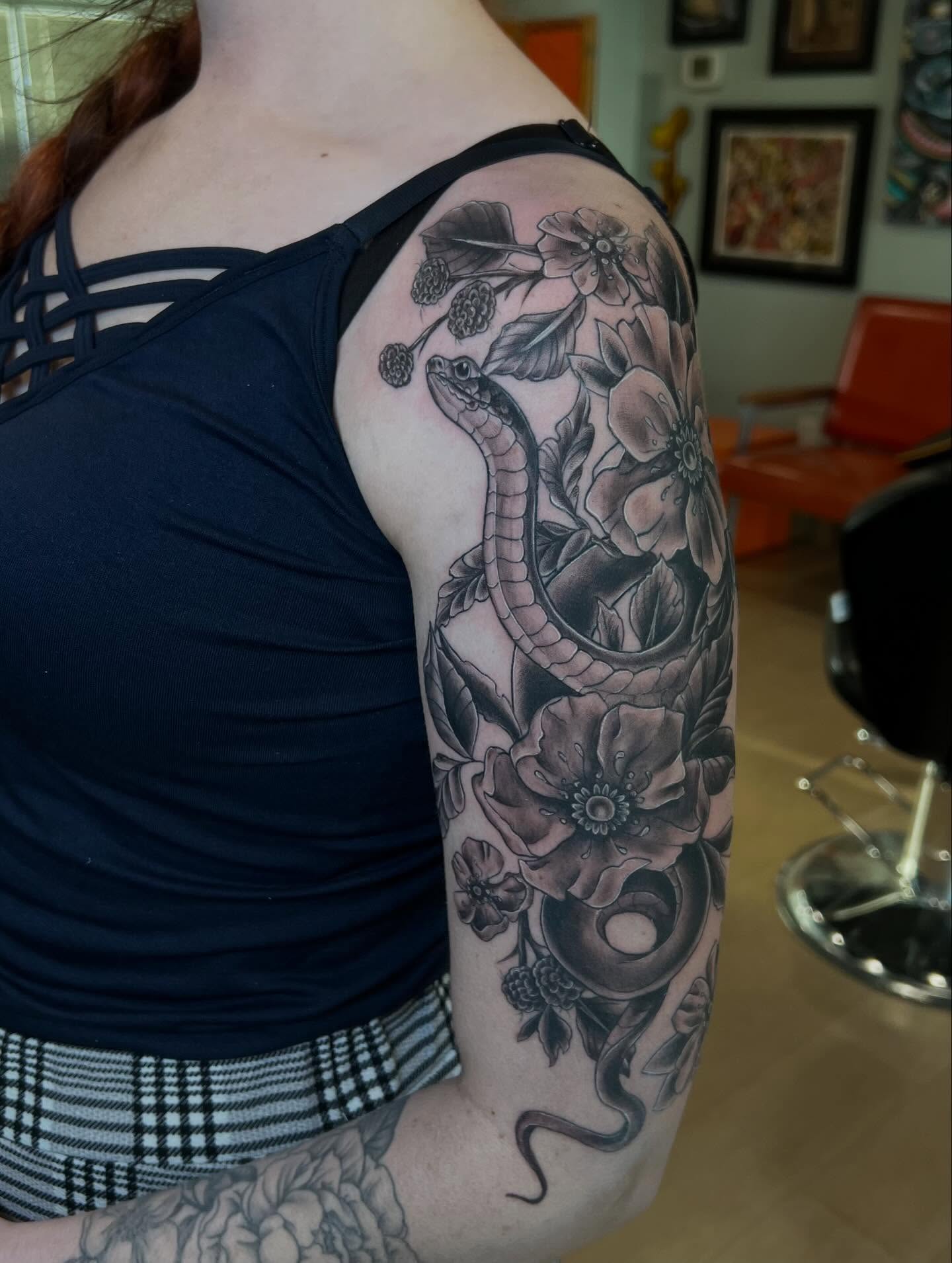 Snake and flowers American traditional tattoo on the upper arm by Jessica Kloos