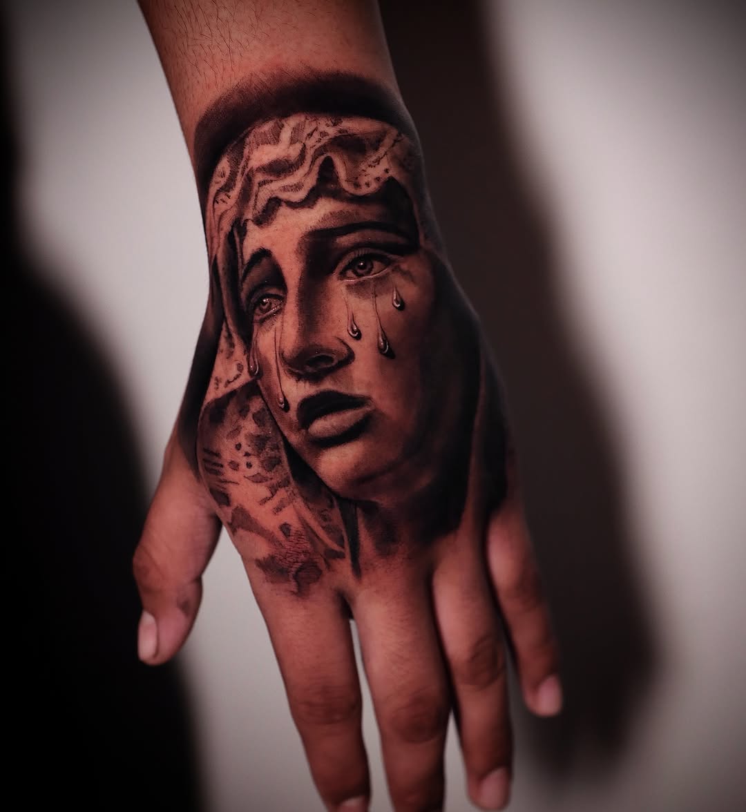 Crying woman's face Chicano tattoo on the hand by elvis flores