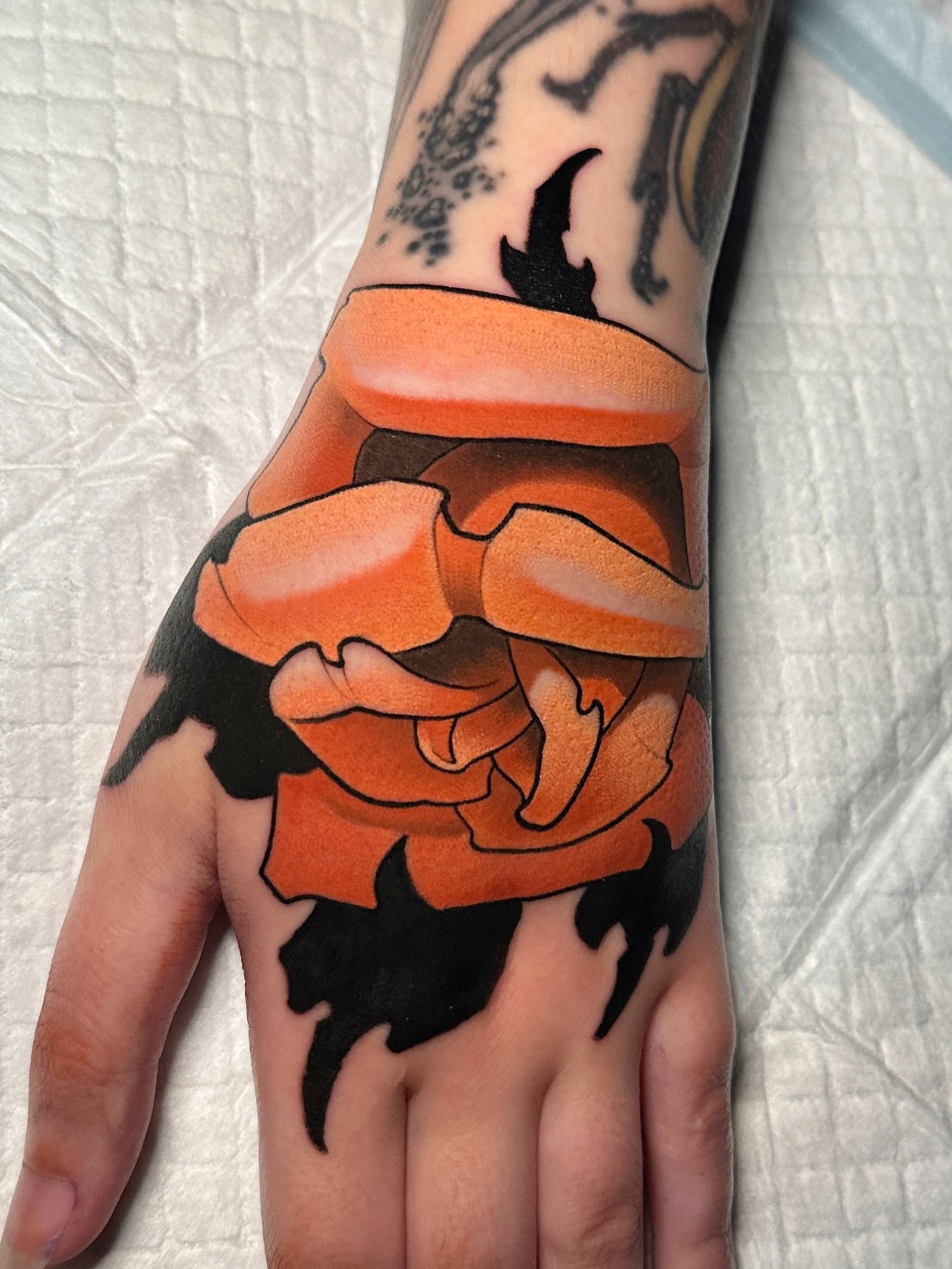 Orange rose American traditional tattoo on the hand by Skylar Mangrum
