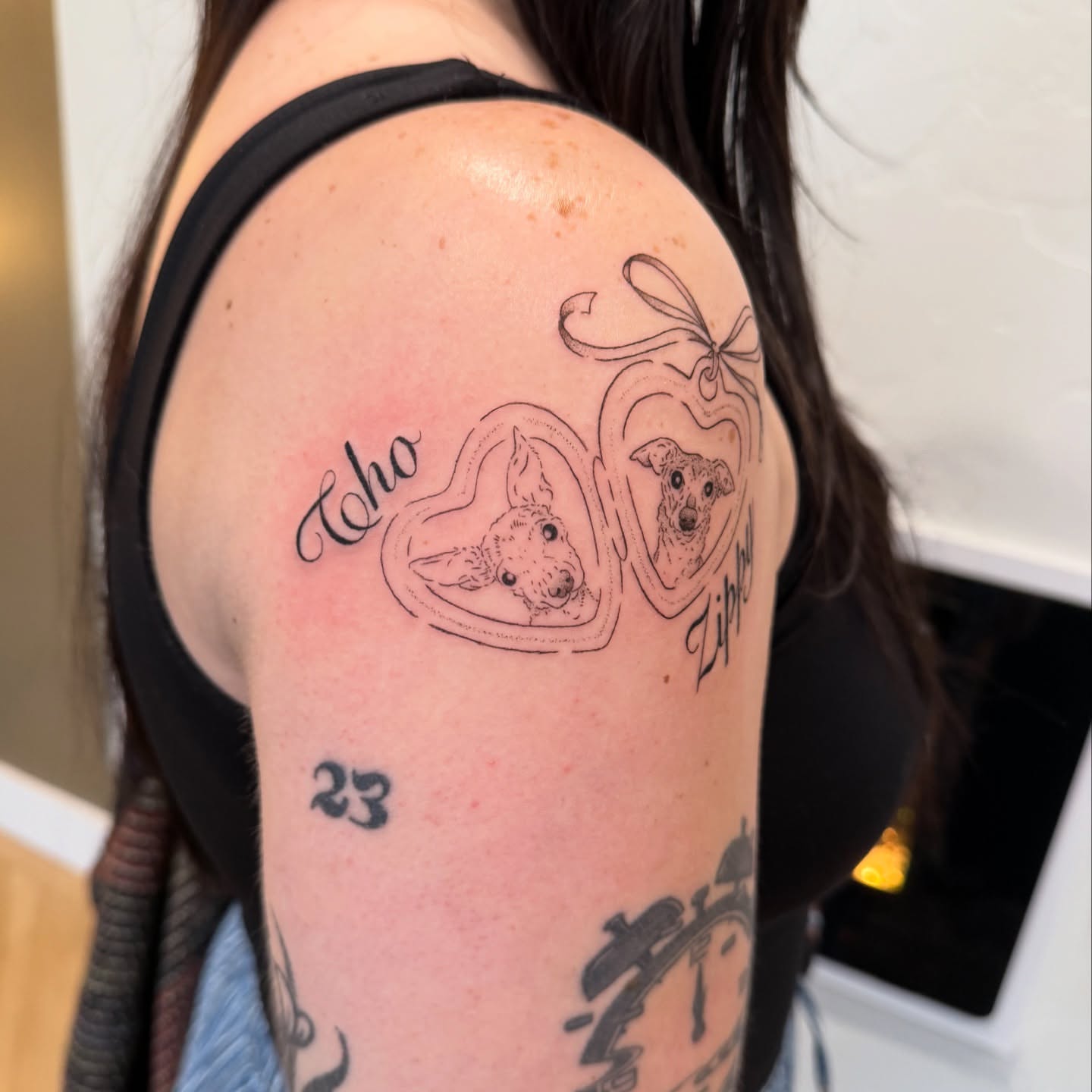 Dogs in hearts black and grey tattoo on the shoulder by Fine Line Tattoos