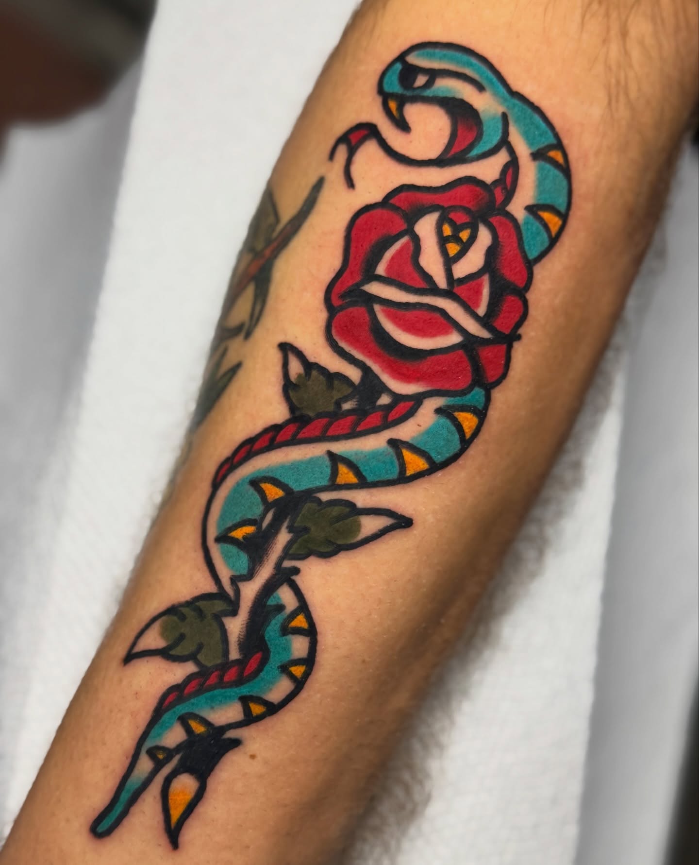 Snake and rose American traditional tattoo on the forearm by Javin Klingelhoefer Mosley