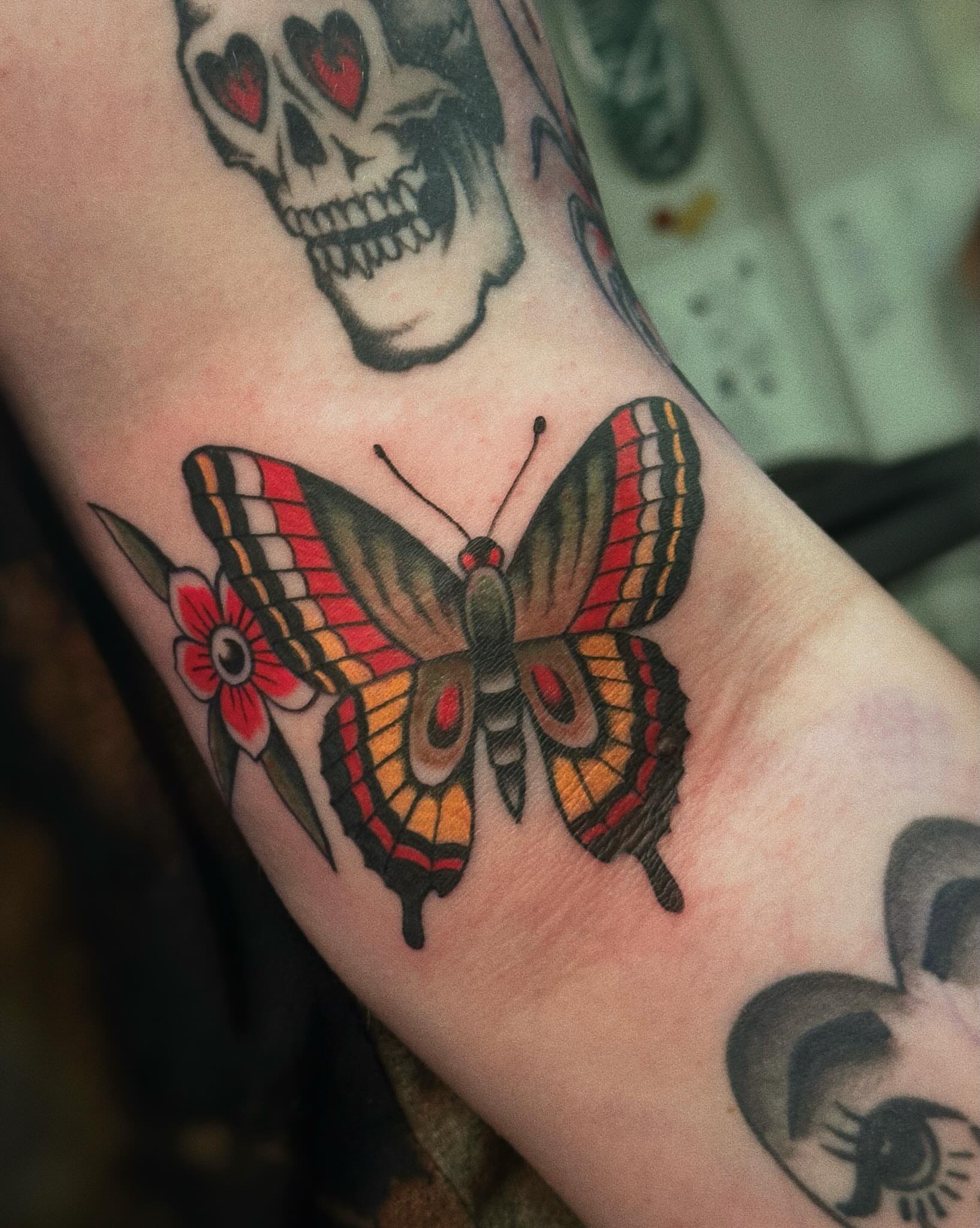Butterfly and flower American traditional tattoo on the forearm by Craig Ryans