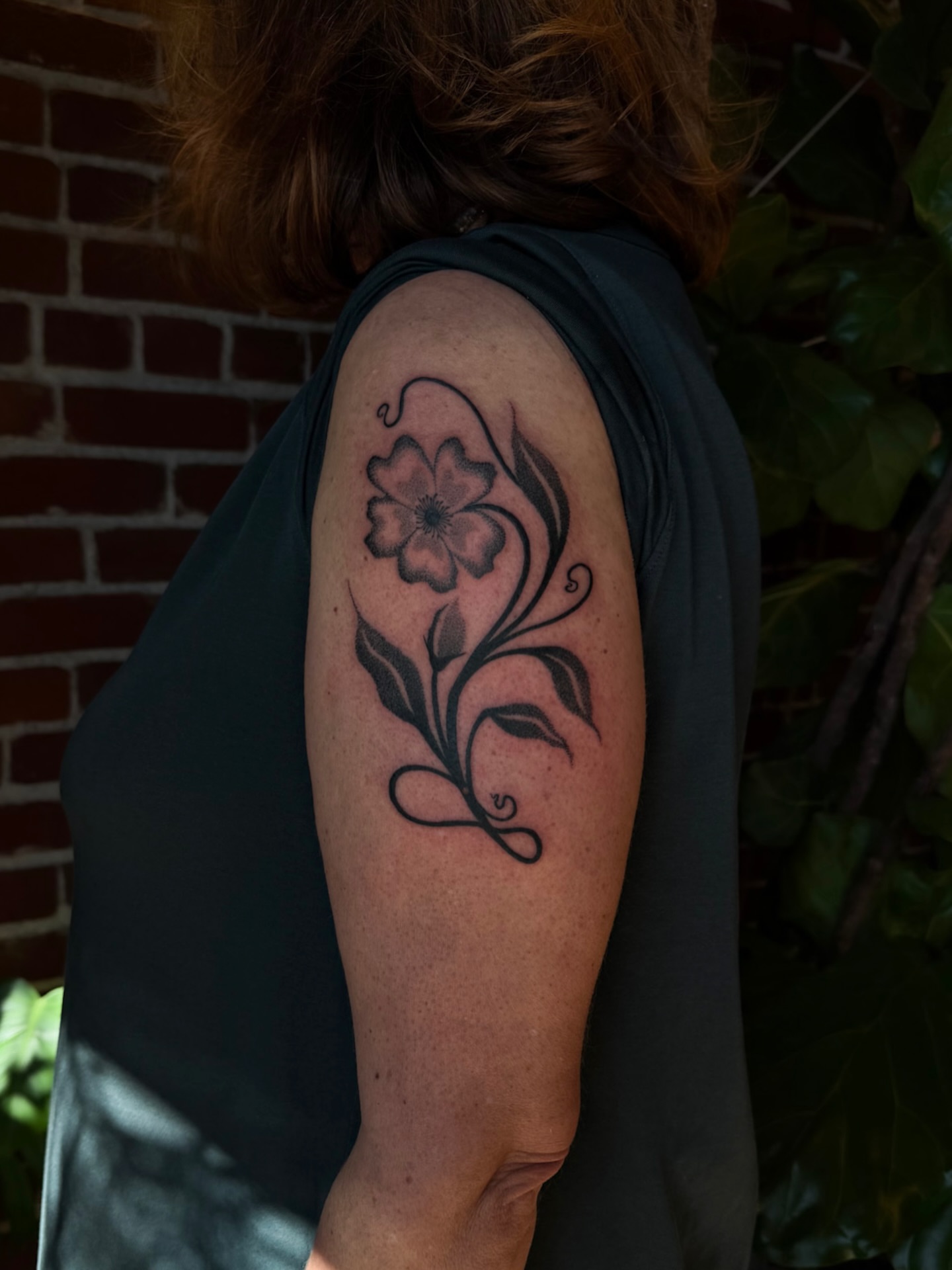 Flower black and grey tattoo on the upper arm by Alexandra Gray