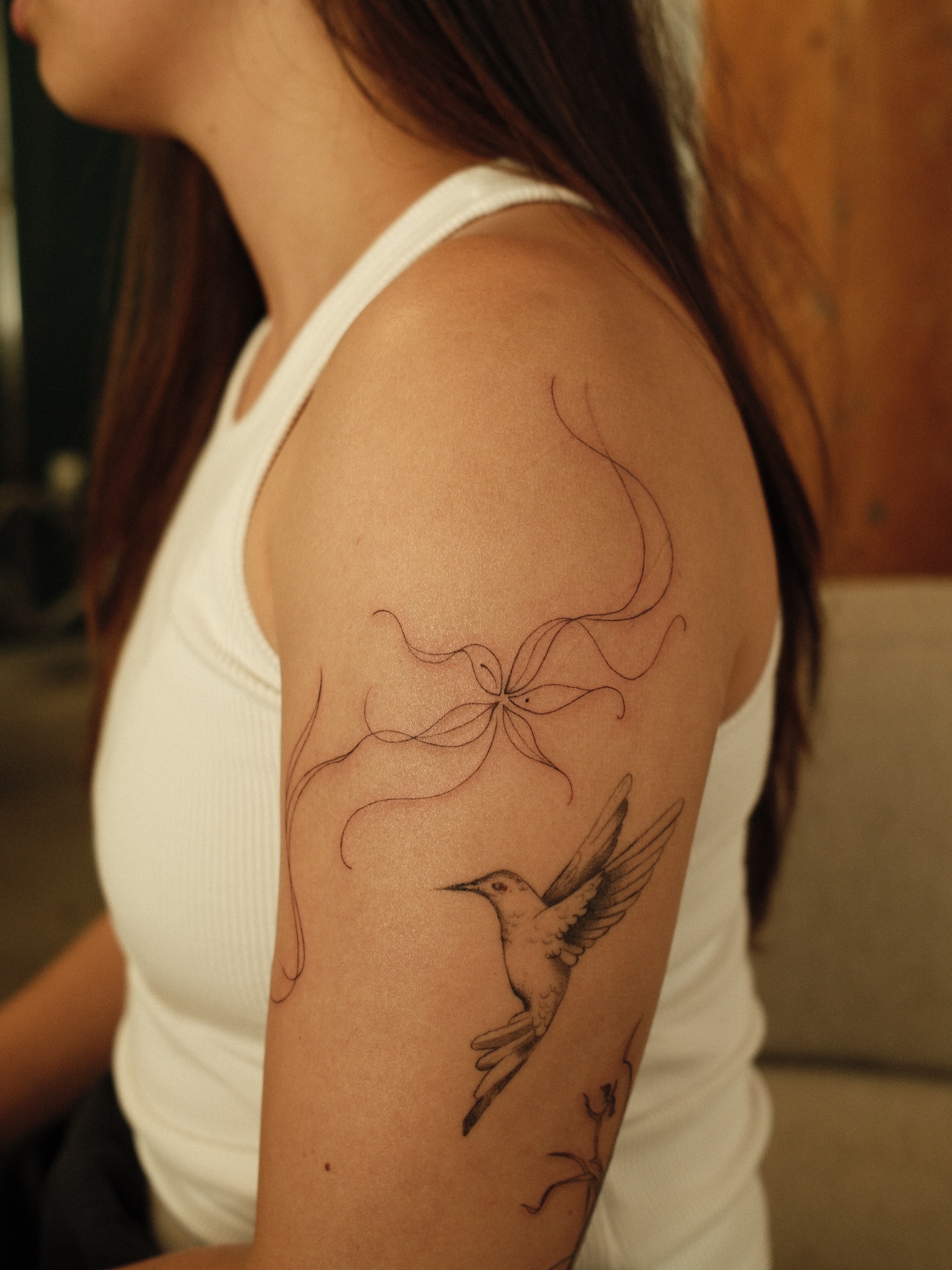 Bird and flower fine line tattoo on the upper arm by v?