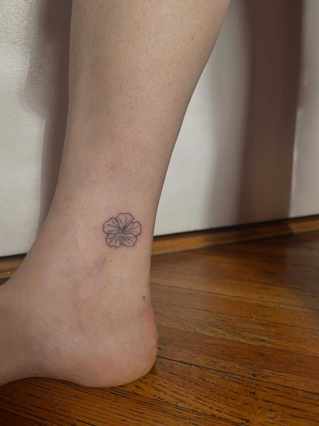 Flower minimalist tattoo on the foot by Emma D
