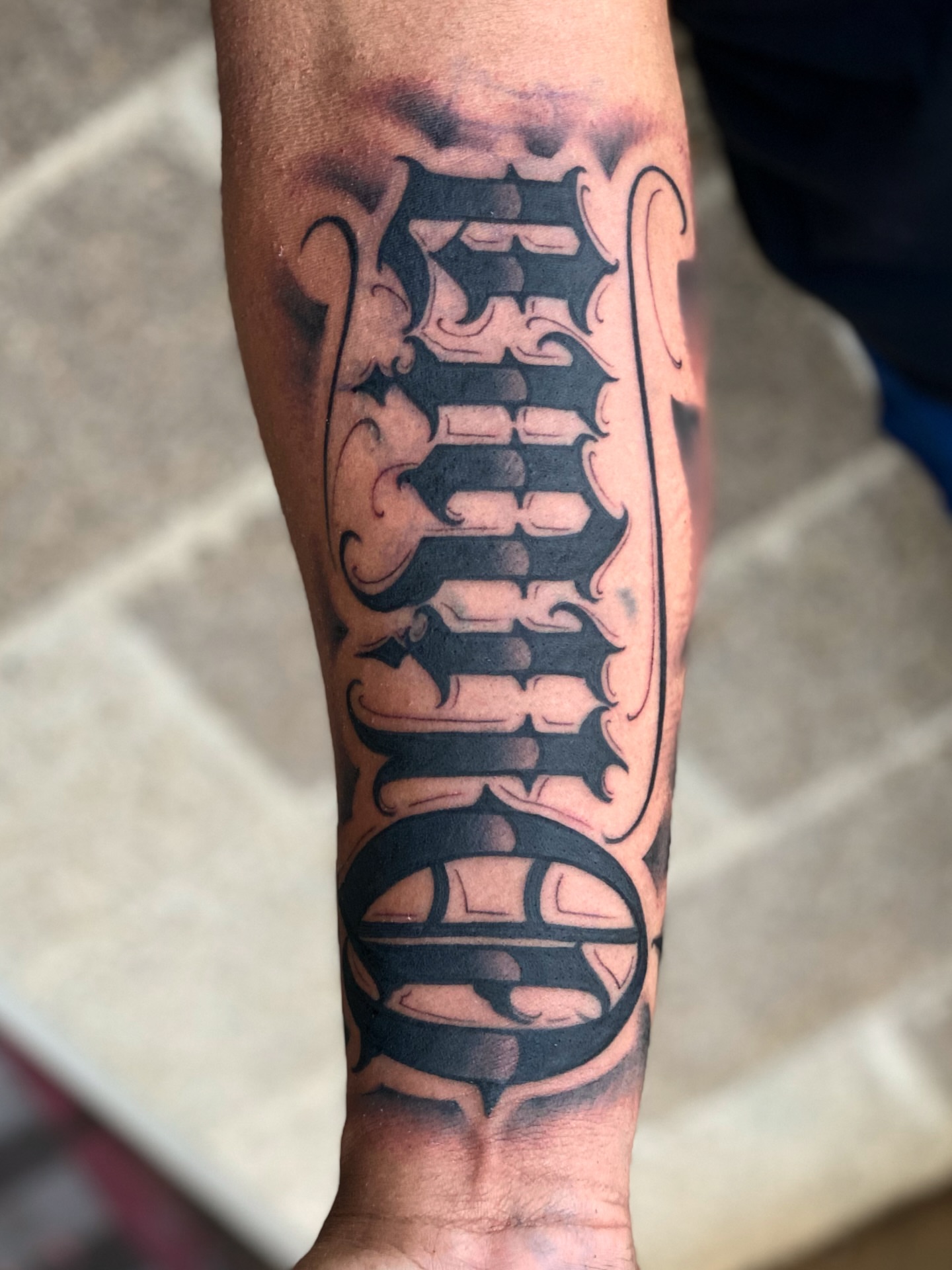 Lettering black and grey tattoo on the forearm by Lex Miranda