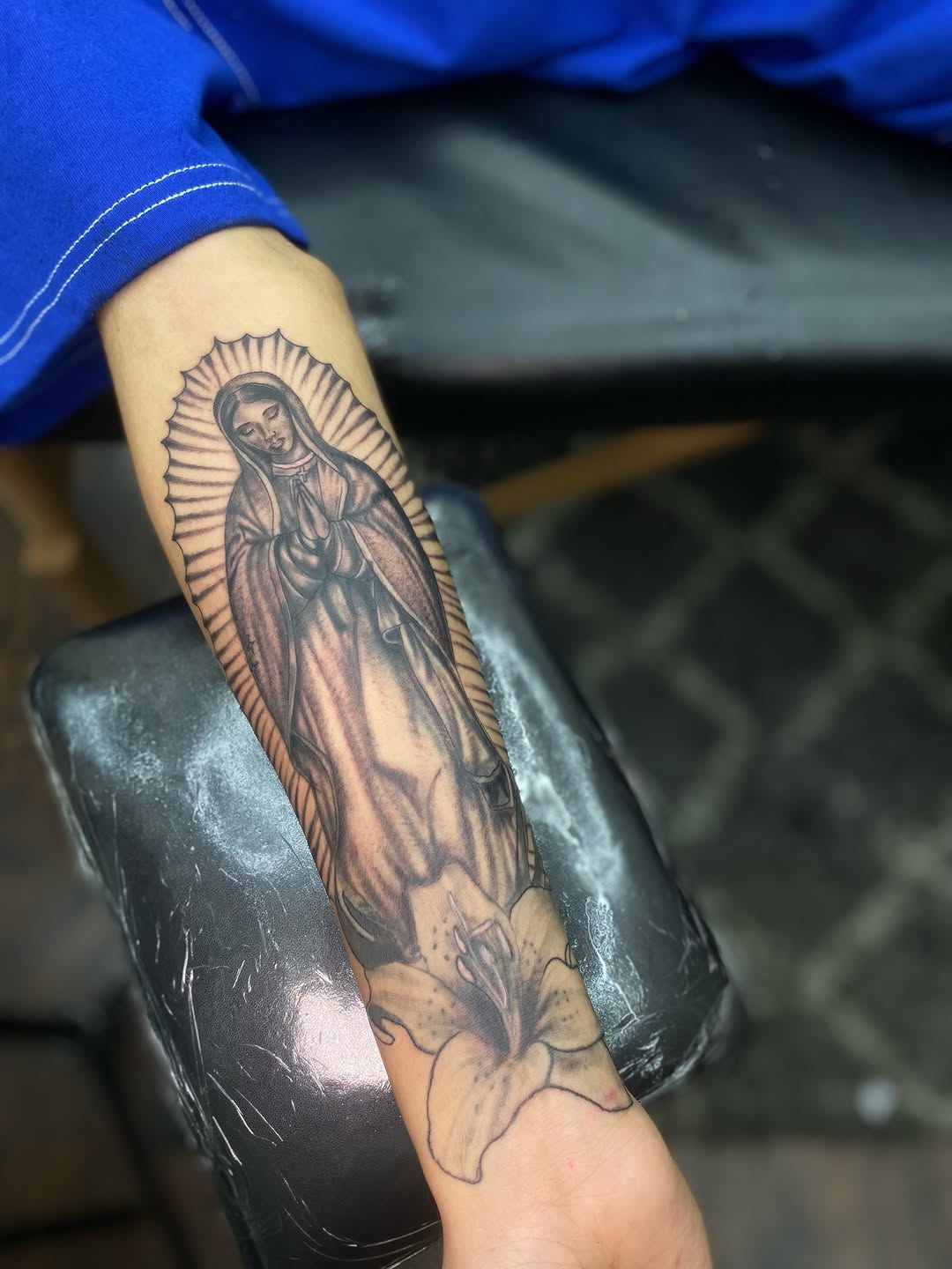 Virgin Mary and lily Chicano tattoo on the forearm by Irving Guzman